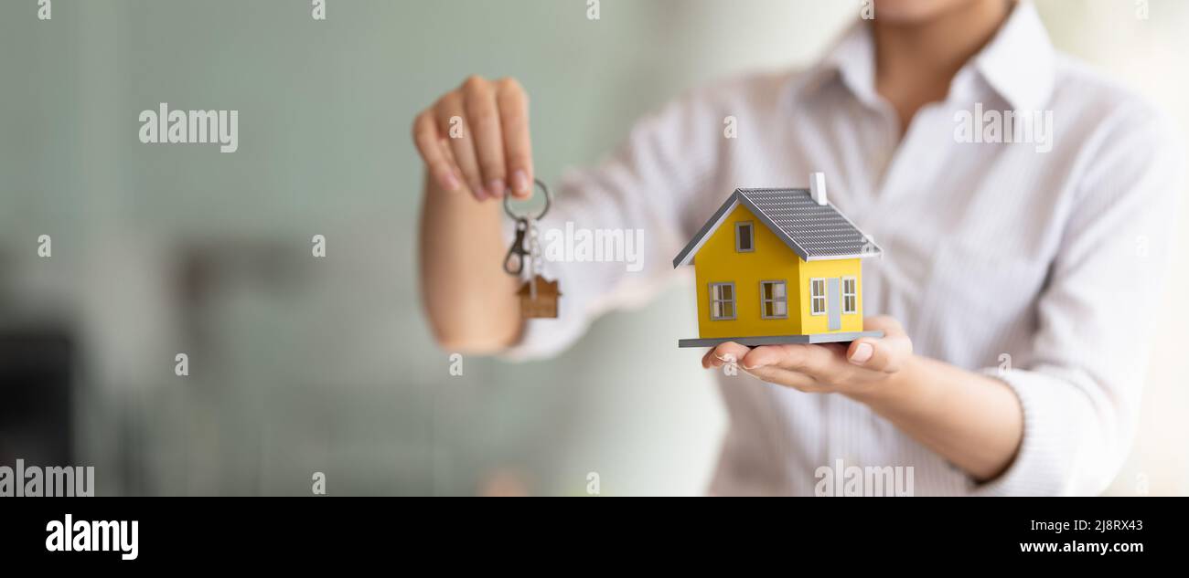 Scatto ritagliato dell'agente immobiliare che consegna le chiavi e il modello domestico. Foto Stock