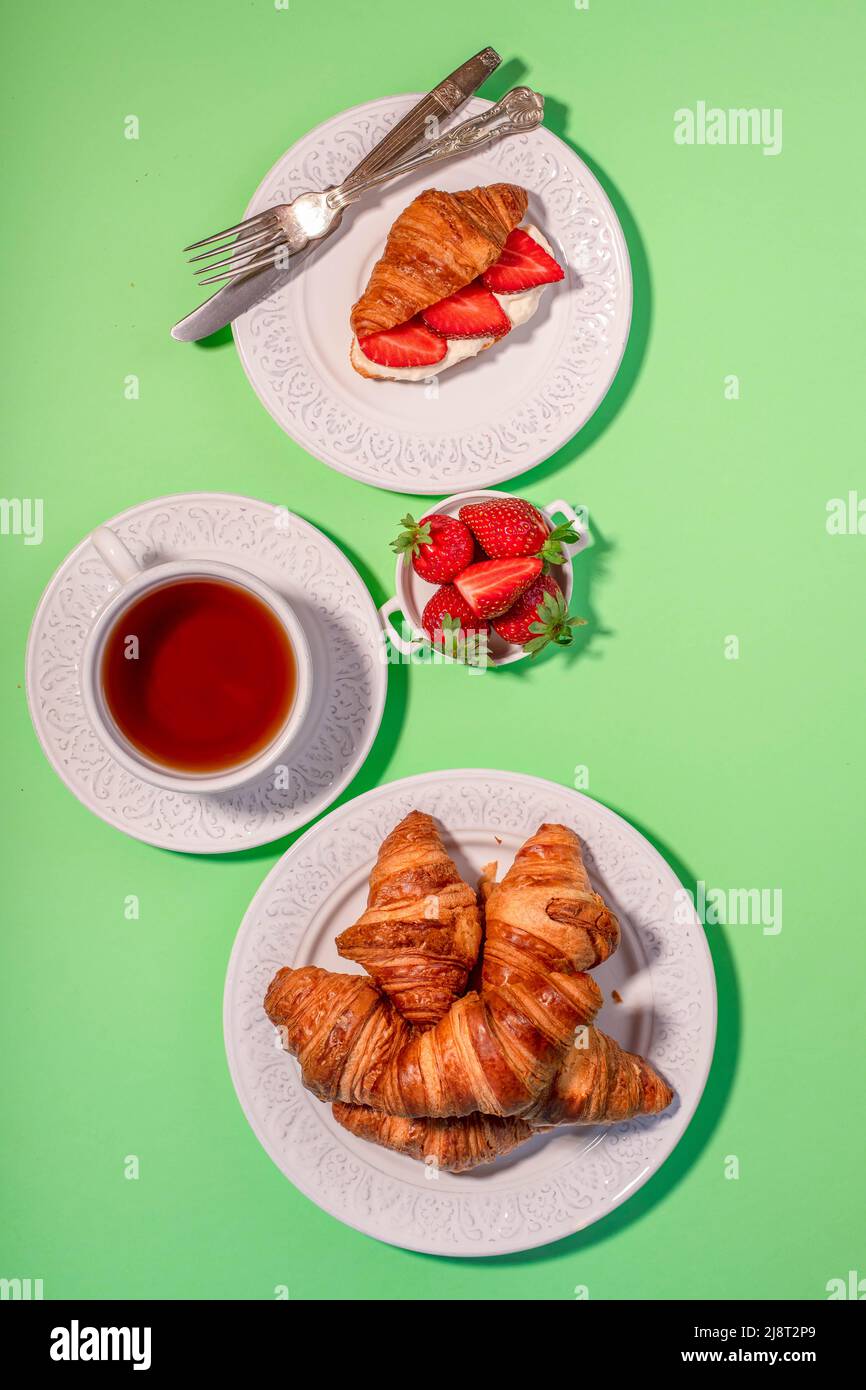 La colazione comprende croissant, fragole fresche, panna sbattuta e una tazza di tè. Foto Stock