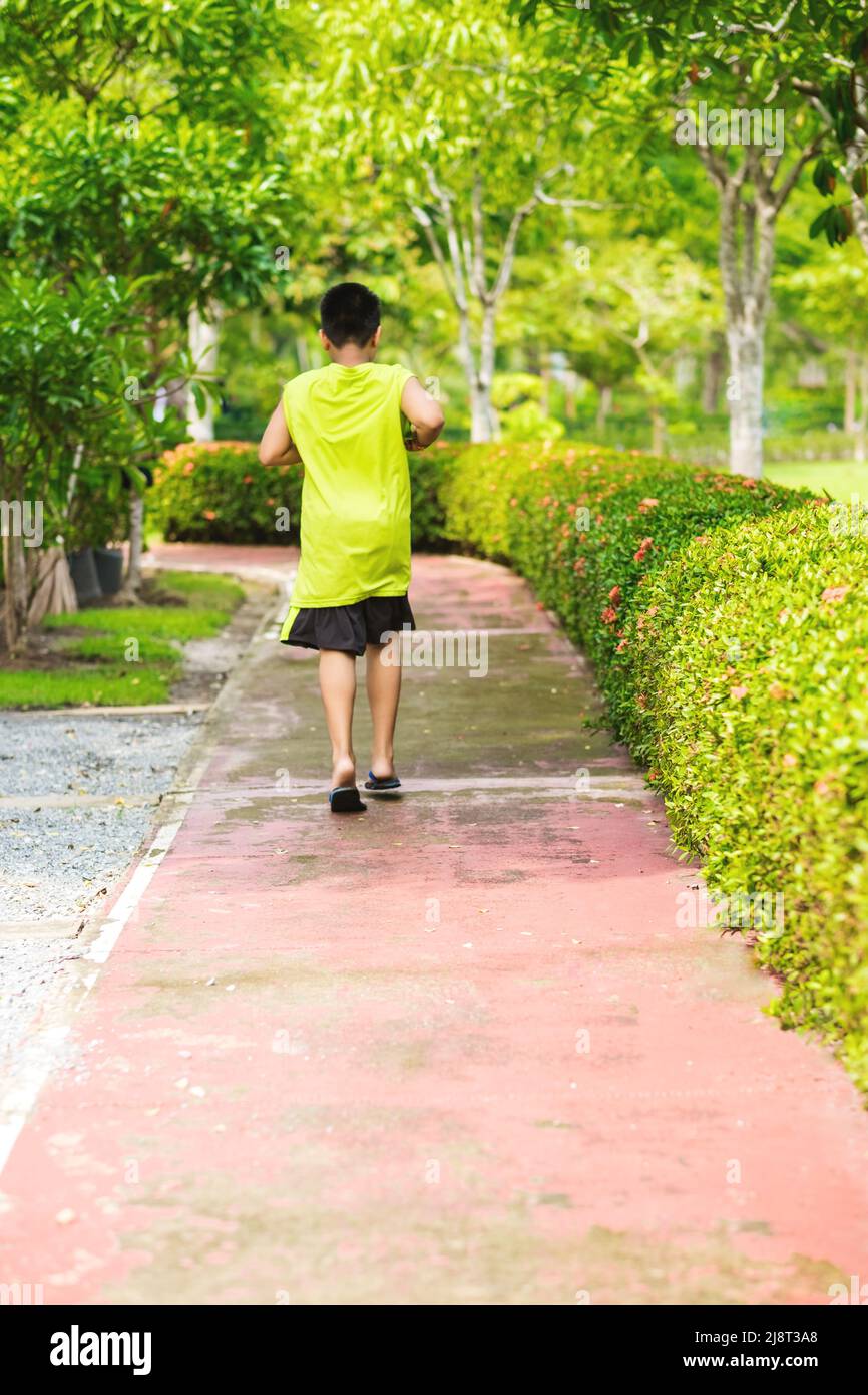 Vista rara del giovane ragazzo asiatico che corre in giardino. Foto Stock