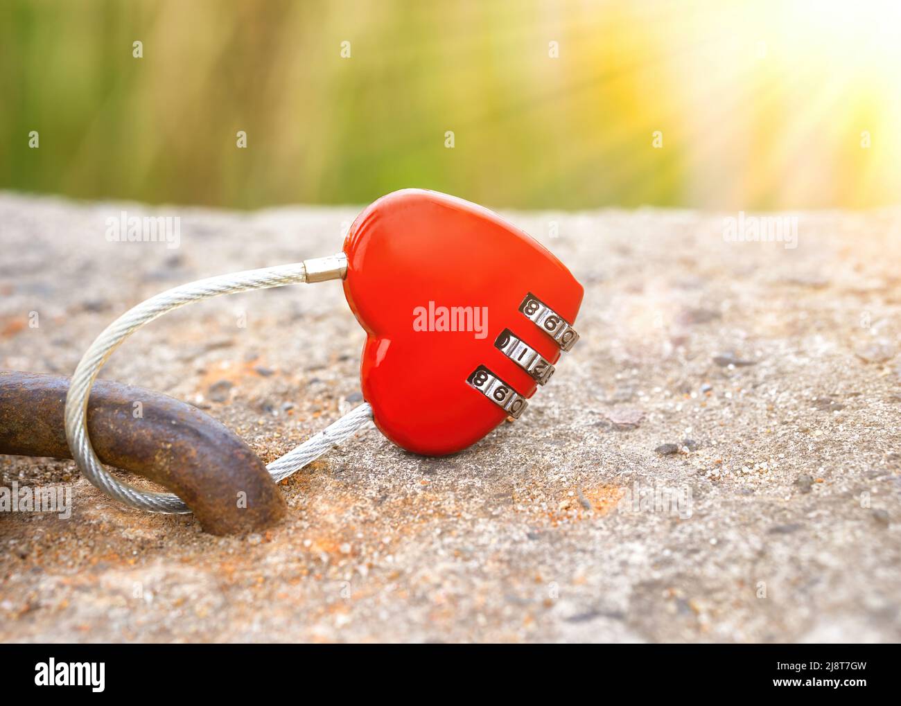 Lucchetto a forma di cuore con cavo chiuso illuminato con raggi solari. Luminoso concetto di amore e impegno. Foto Stock