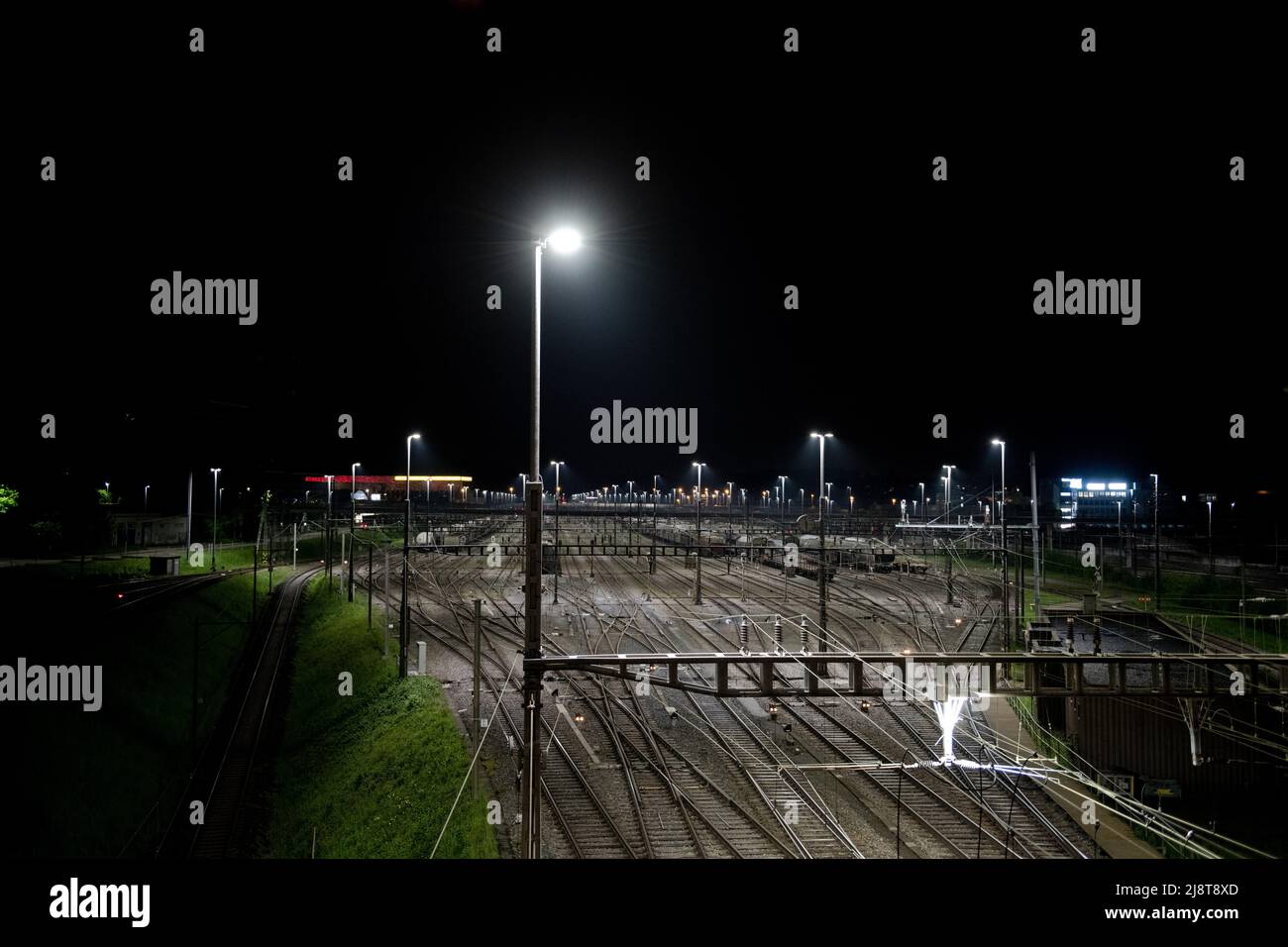 Stazione di trasporto di notte a Zurigo, Spreitenbach. I treni merci sono illuminati da fari luminosi. Sullo sfondo si trova uno strato di nebbia. Foto Stock