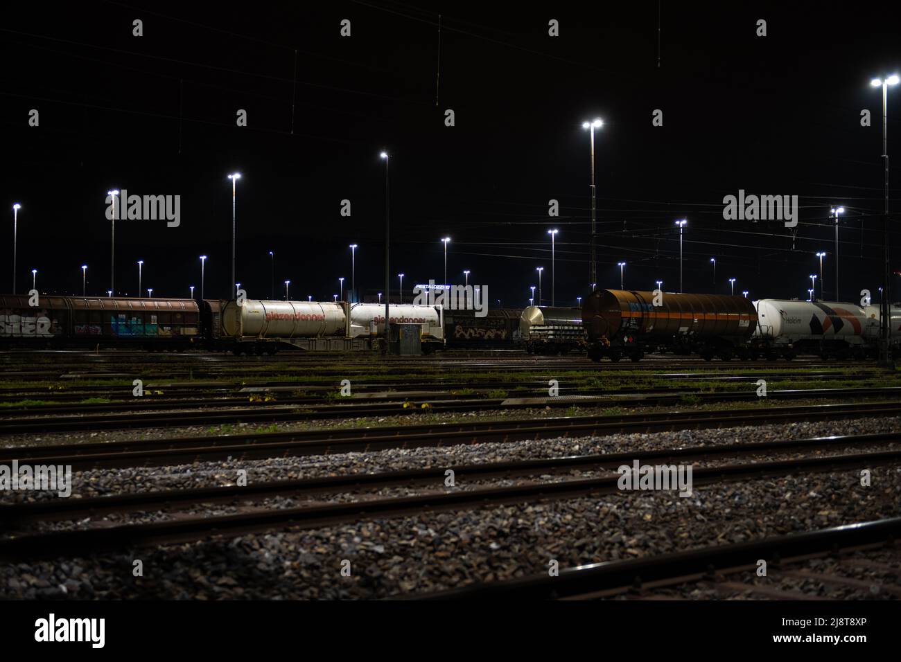 Stazione di trasporto di notte a Zurigo, Spreitenbach. I treni merci sono illuminati da fari luminosi. Foto Stock