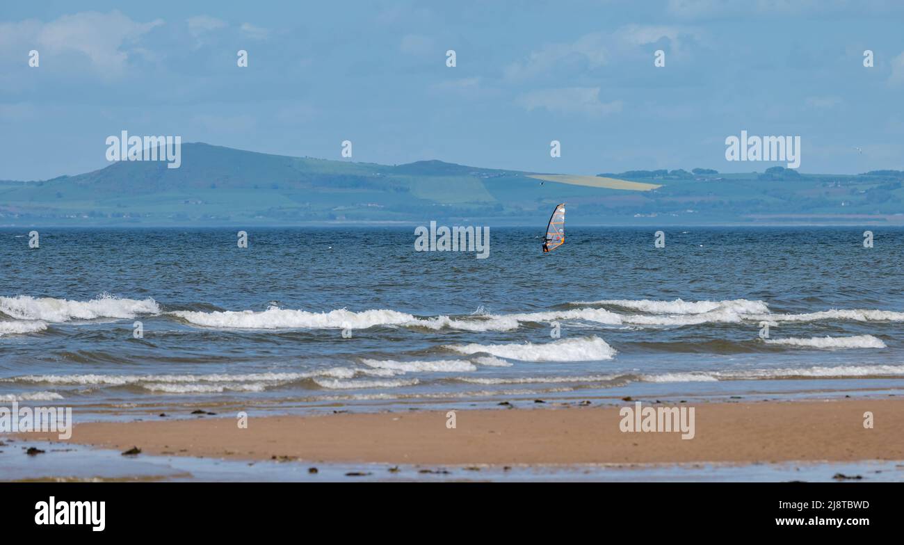 East Lothian, Scozia, Regno Unito, 18th maggio 2022. UK Meteo: Breezy sole sulla costa. Un windsurfer naviga nelle onde nel Firth of Forth vicino alla spiaggia di Aberlady Foto Stock