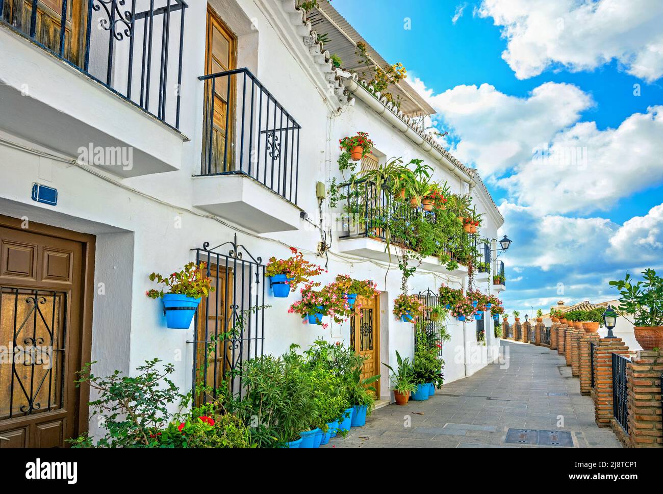 Pittoresca strada stretta e tipica facciata di casa bianca decorata con vasi di fiori blu a Mijas. Provincia di Malaga, Andalusia, Spagna Foto Stock