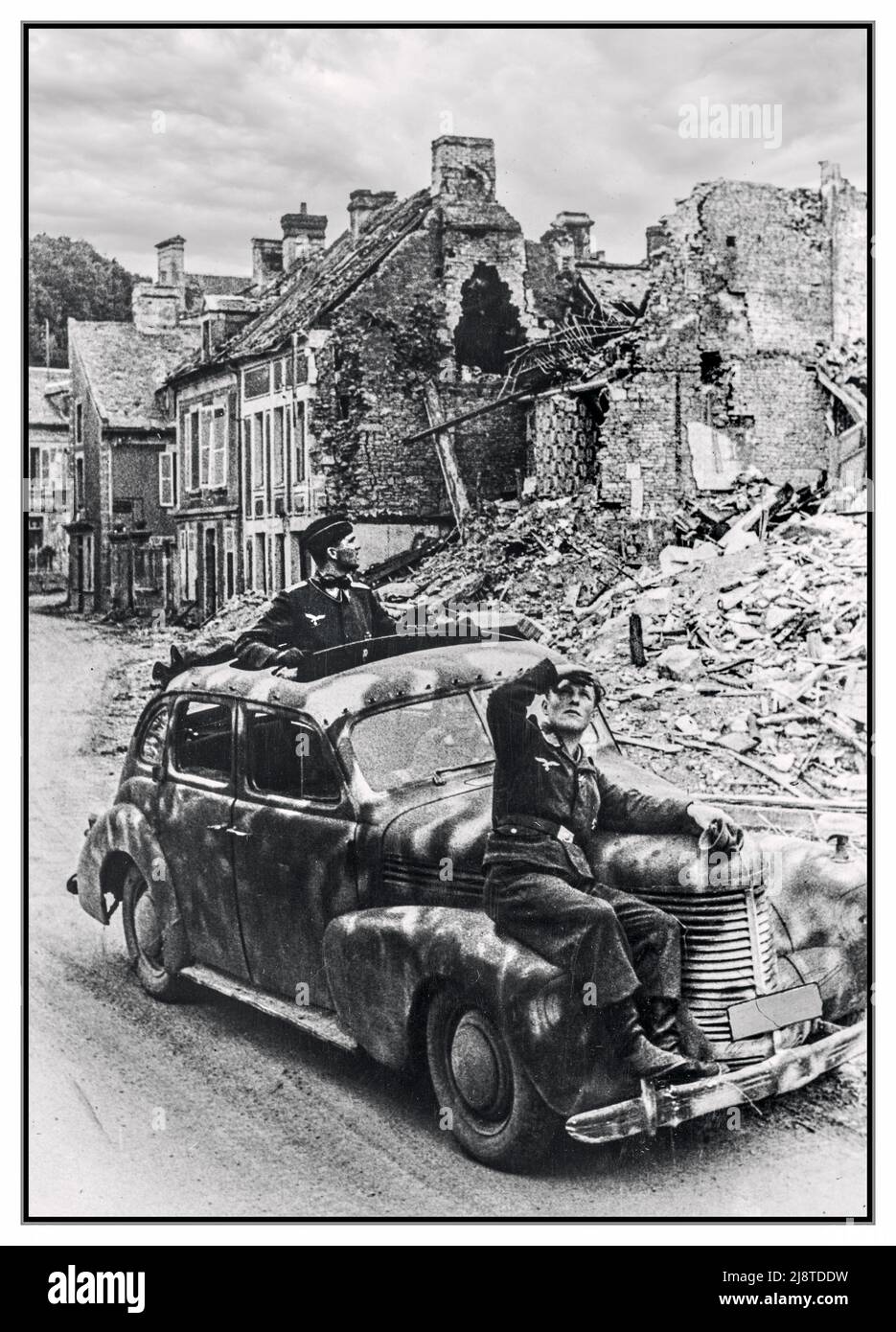 D-Day ritiro ad hoc tedesco in un camuffato auto del personale Opel 'Kapitan', con tre soldati nazisti Wehrmacht tedesco che guardano fuori per gli attacchi alleati, guida e ritirarsi tra le rovine di una città in Normandia. Operazione Overlord, Normandia sbarco D-Day Francia luglio 1944 Foto Stock