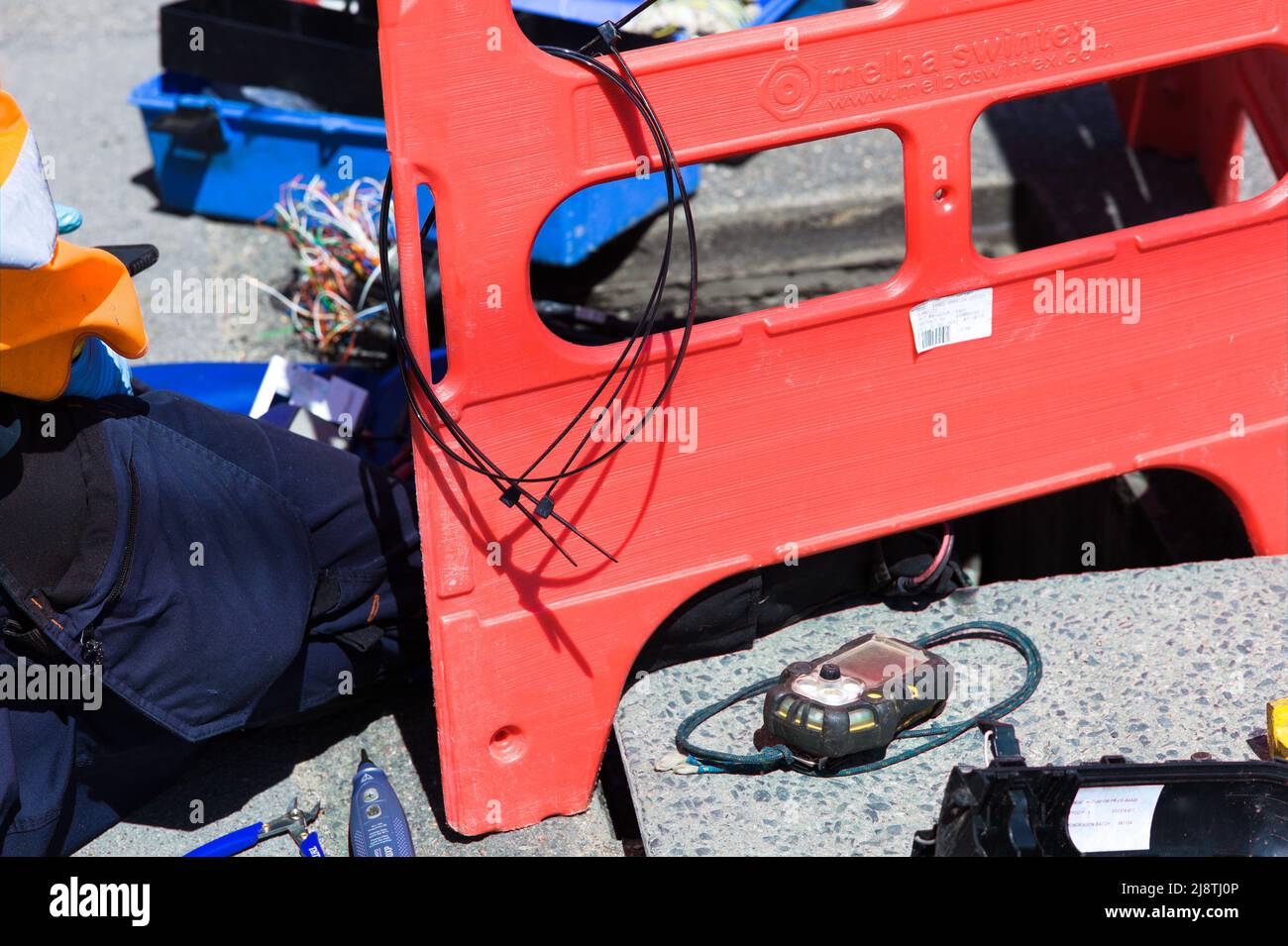 Vista astratta di un tecnico Open Reach Communications che lavora per riparare il cablaggio lato strada. Foto Stock