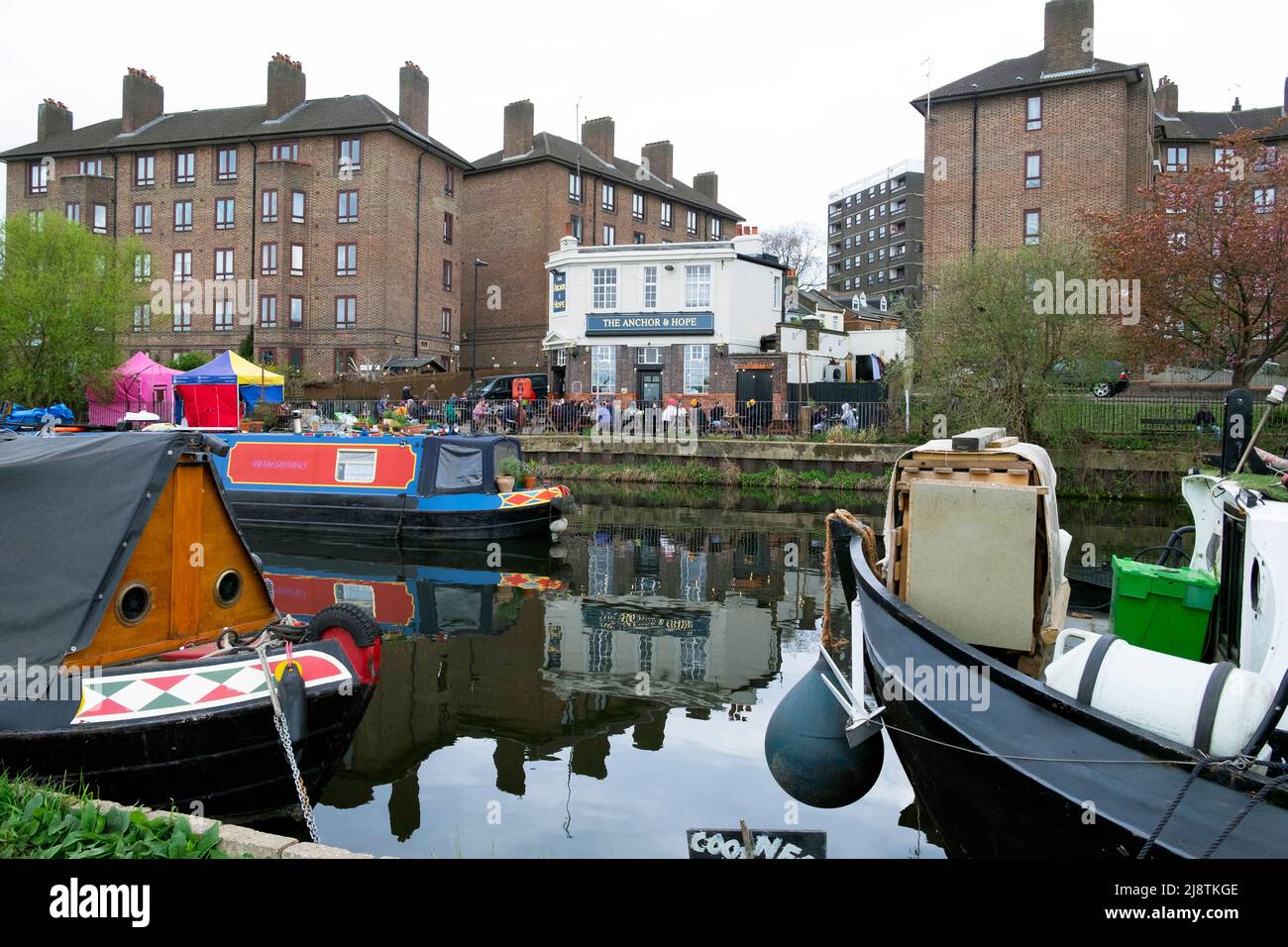 Vista del tradizionale Anchor e Hope inglese Fullers pub lungo il fiume e barche case galleggianti sul fiume Lea Clapton Londra E5 Inghilterra Regno Unito KATHY DEWITT Foto Stock