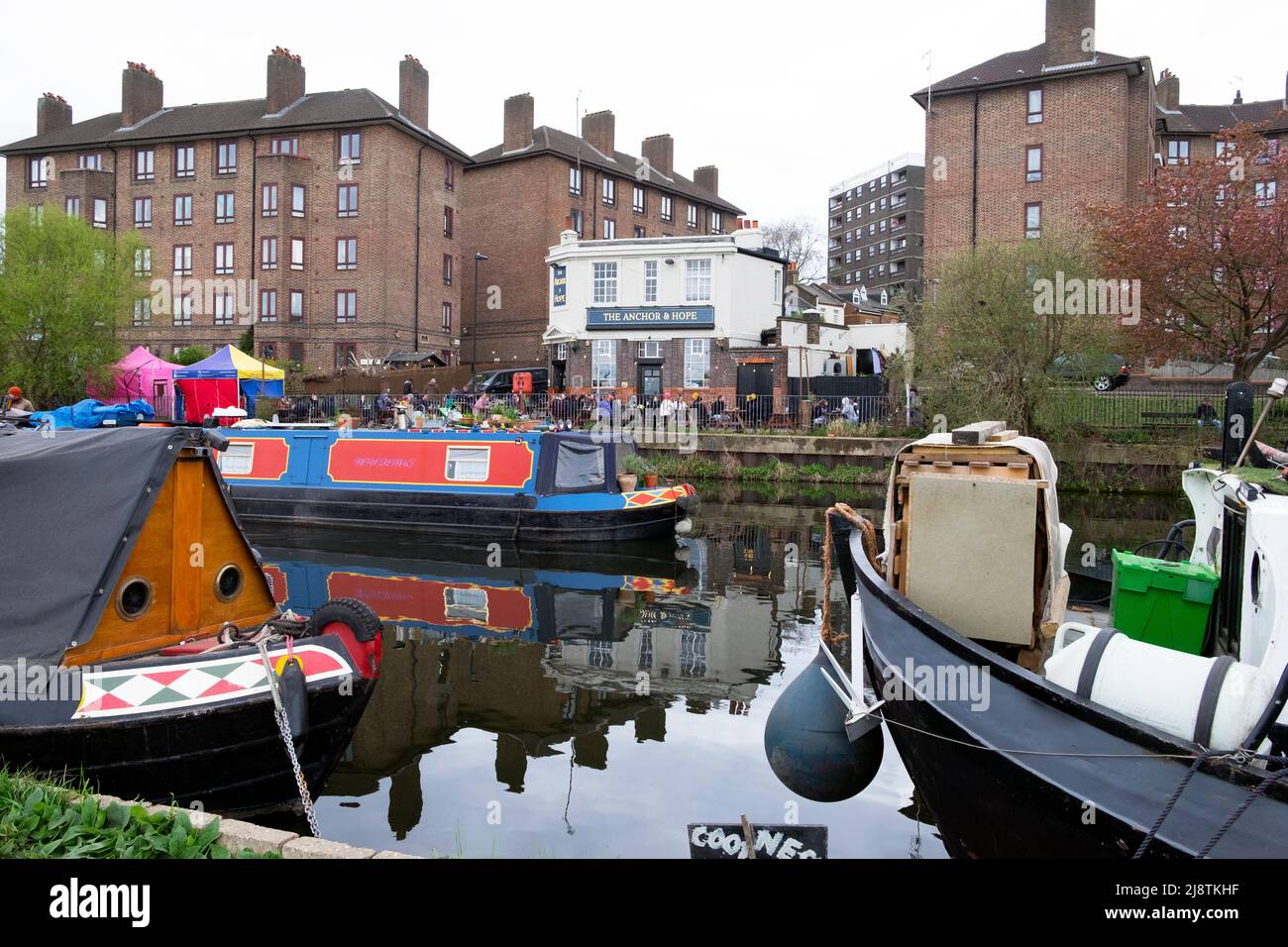 Vista del tradizionale Anchor e Hope inglese Fullers pub lungo il fiume e barche case galleggianti sul fiume Lea Clapton Londra E5 Inghilterra Regno Unito KATHY DEWITT Foto Stock