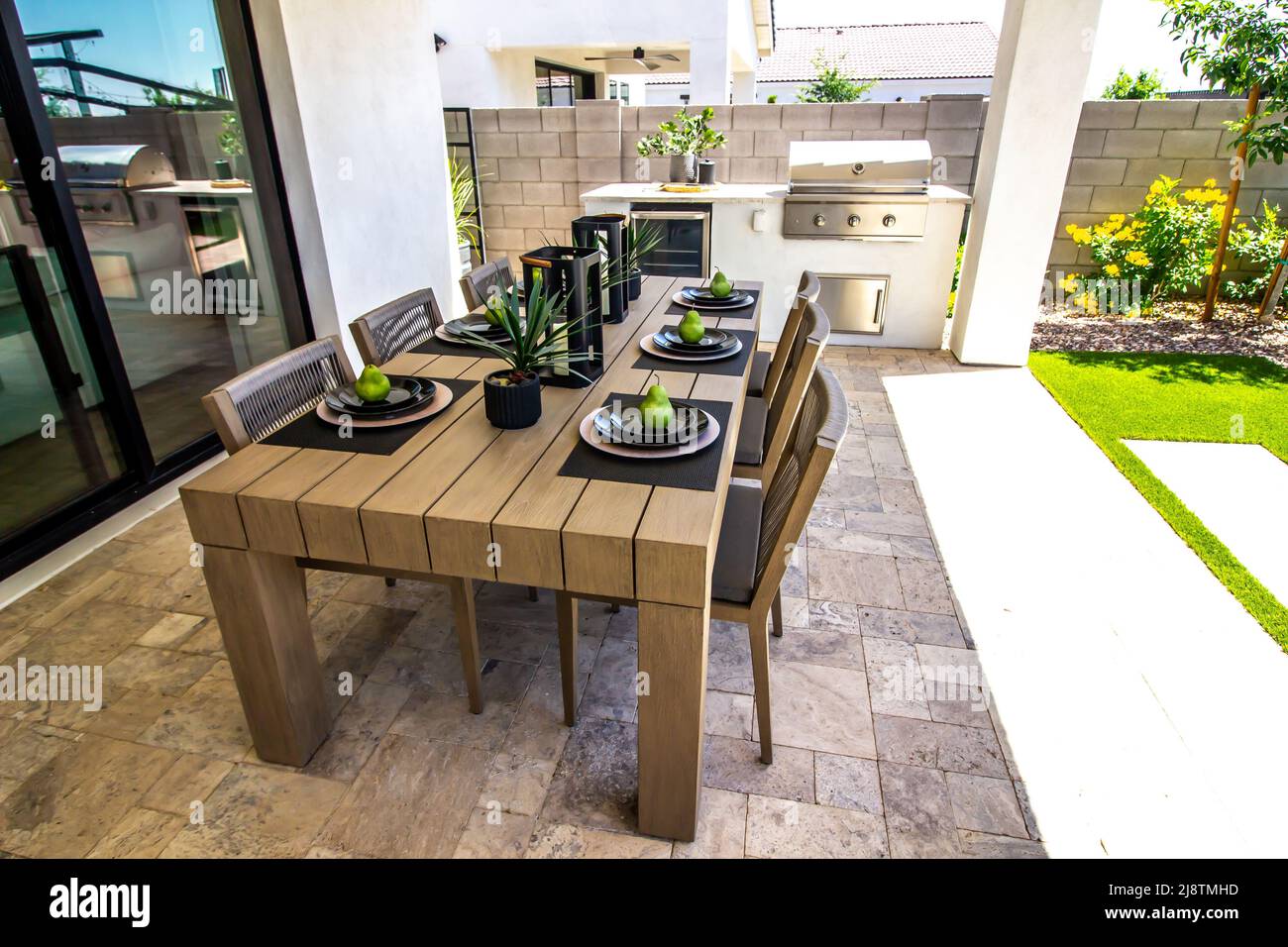 Patio posteriore con giardino, sedie e barbecue incorporato Foto Stock