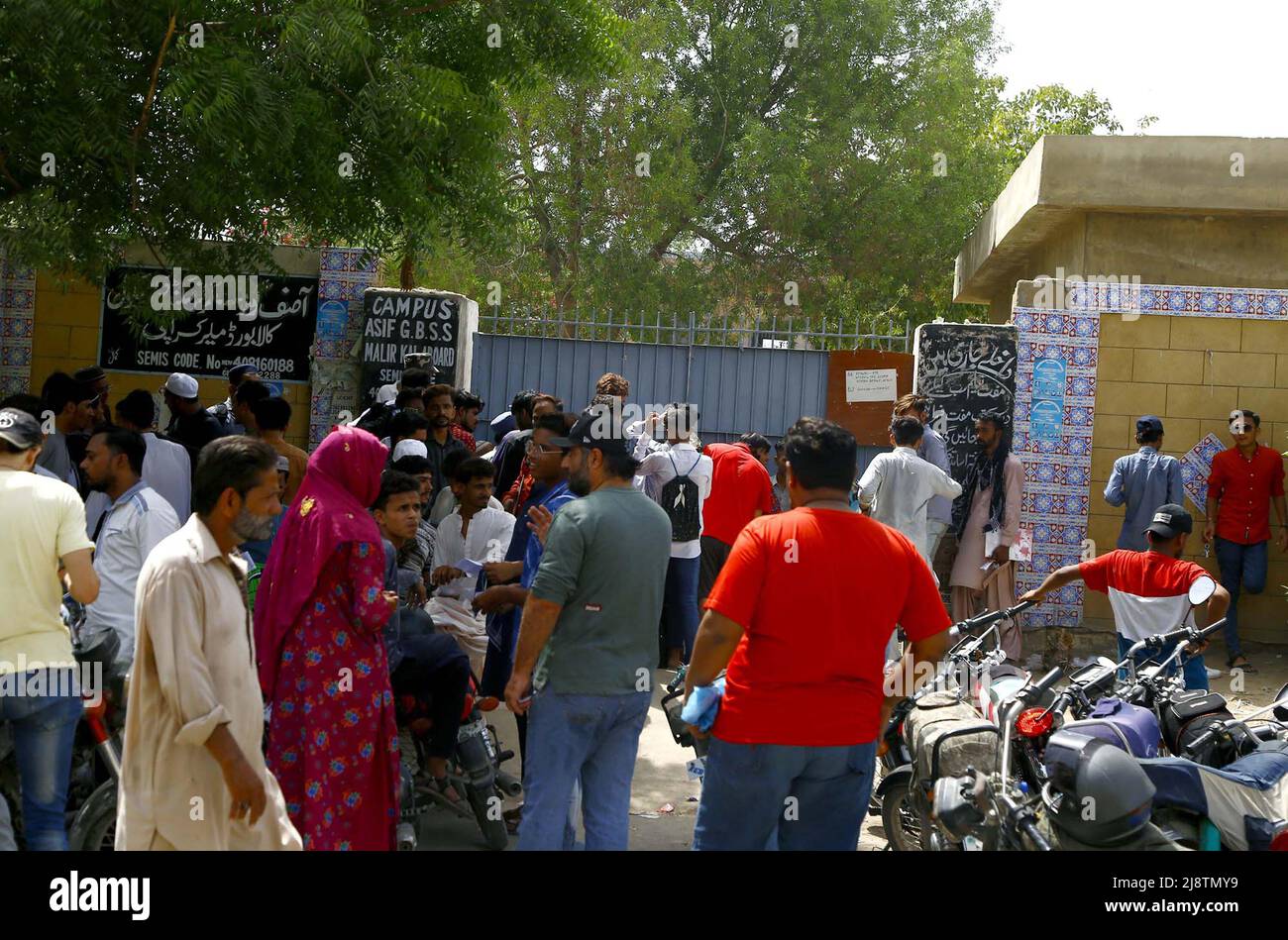 I genitori e gli studenti si riuniscono fuori dal centro di esame in una calda giornata estiva durante l'esame annuale di Matriculation 2022 sotto la supervisione del Consiglio di Istruzione secondaria e secondaria superiore, situato nell'area del Consiglio di Amministrazione di Malir Kala a Karachi mercoledì 18 maggio 2022. Foto Stock