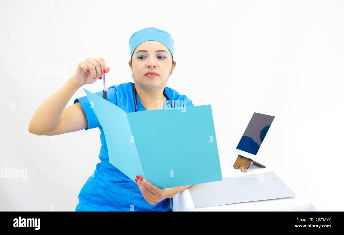 bella donna medico, con cappuccio chirurgico blu uniforme e blu, stetoscopio sul collo, utilizzando la compressa per mostrare i risultati, su sfondo bianco Foto Stock