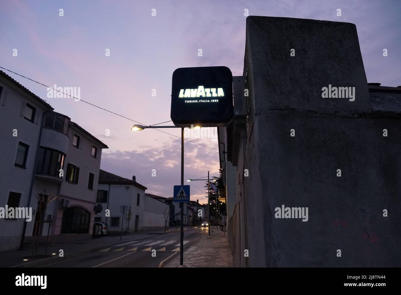 Scudo illuminato con logo di Lavazza situato nella vecchia strada di Capodistria durante il tramonto. Foto Stock