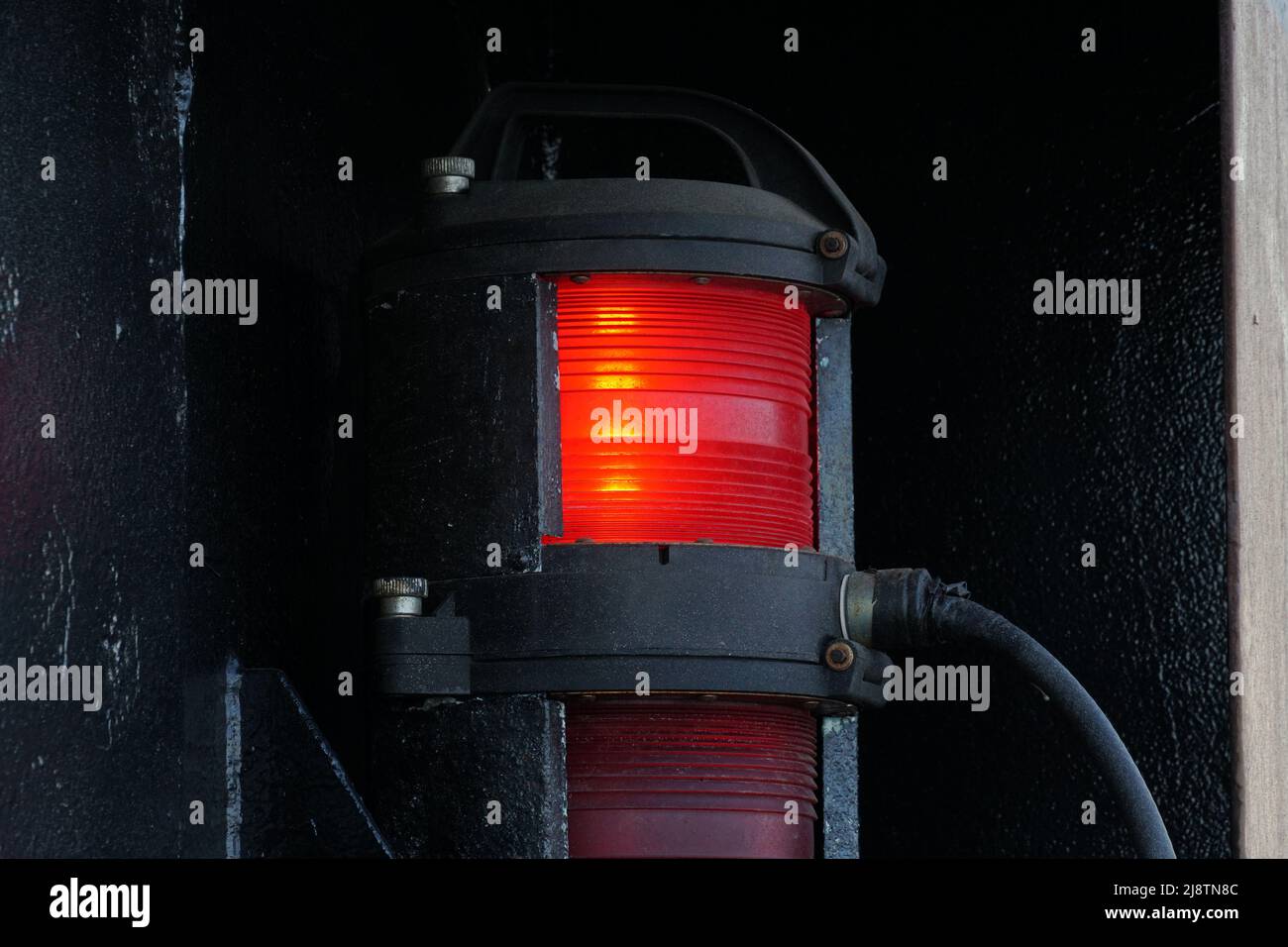 Vista ravvicinata delle luci di navigazione rosse sul lato del porto della nave portacontainer. Foto Stock