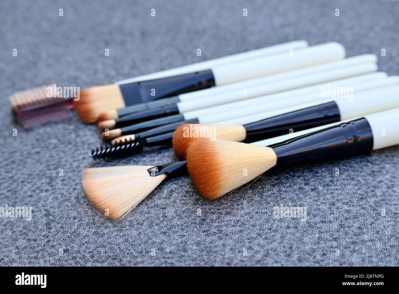 closeup il mazzo bianco marrone makeup kit spazzolare su sfondo grigio marrone fuori fuoco. Foto Stock