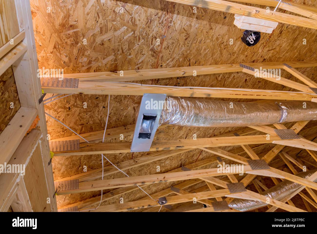 Tubi di ventilazione in color argento per il materiale di isolamento che pendevano dal soffitto all'interno di edificio di nuova costruzione. Foto Stock