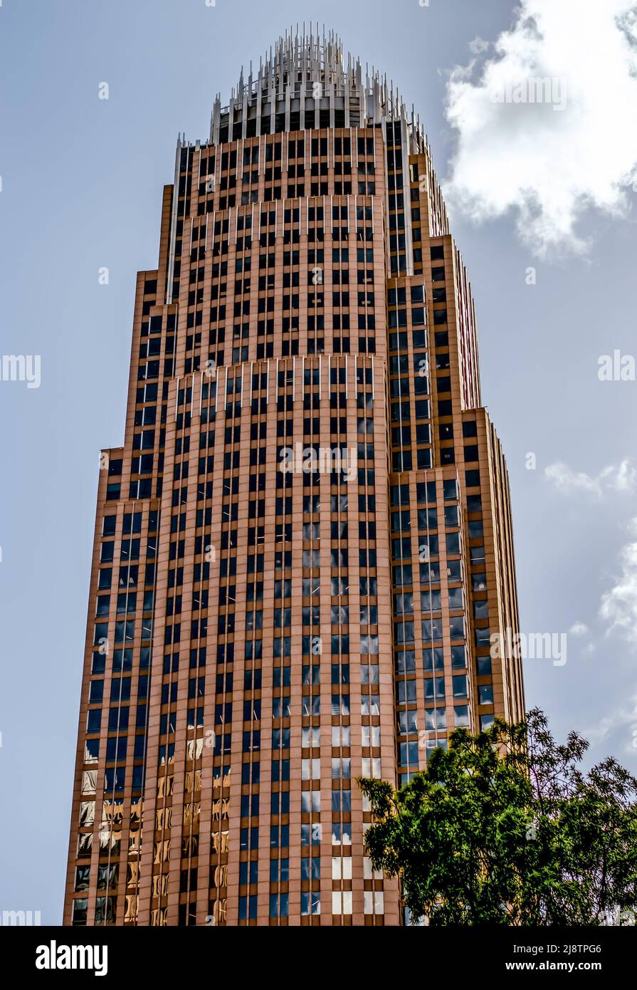 Esterno della sede centrale di Bank of America contro un cielo limpido con una nuvola luminosa, finestre, pavimenti e verde nel centro di Charlotte, NC. Foto Stock