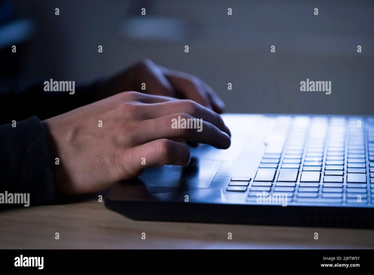 L'uomo sta digitando su una tastiera del laptop, le mani si stanno riutilizzando. Foto Stock