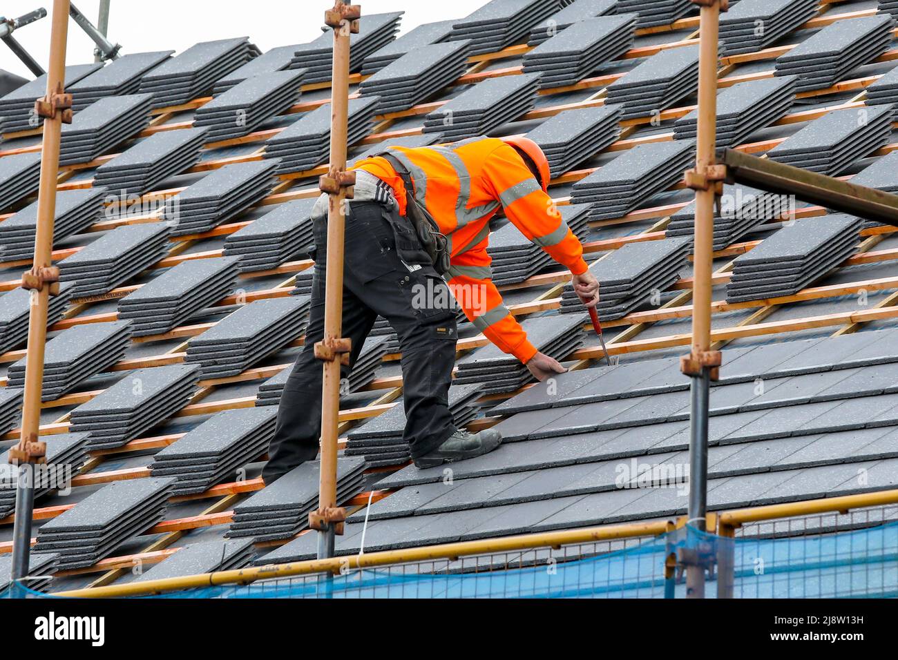 Workman su un tetto su una nuova costruzione casa, Irvine, Ayrshire, Scozia, Regno Unito Foto Stock