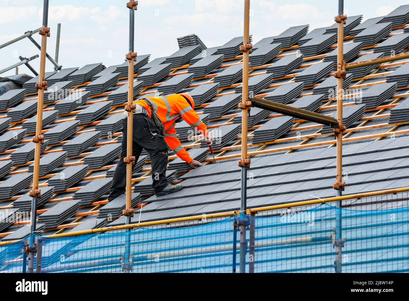 Workman su un tetto su una nuova costruzione casa, Irvine, Ayrshire, Scozia, Regno Unito Foto Stock