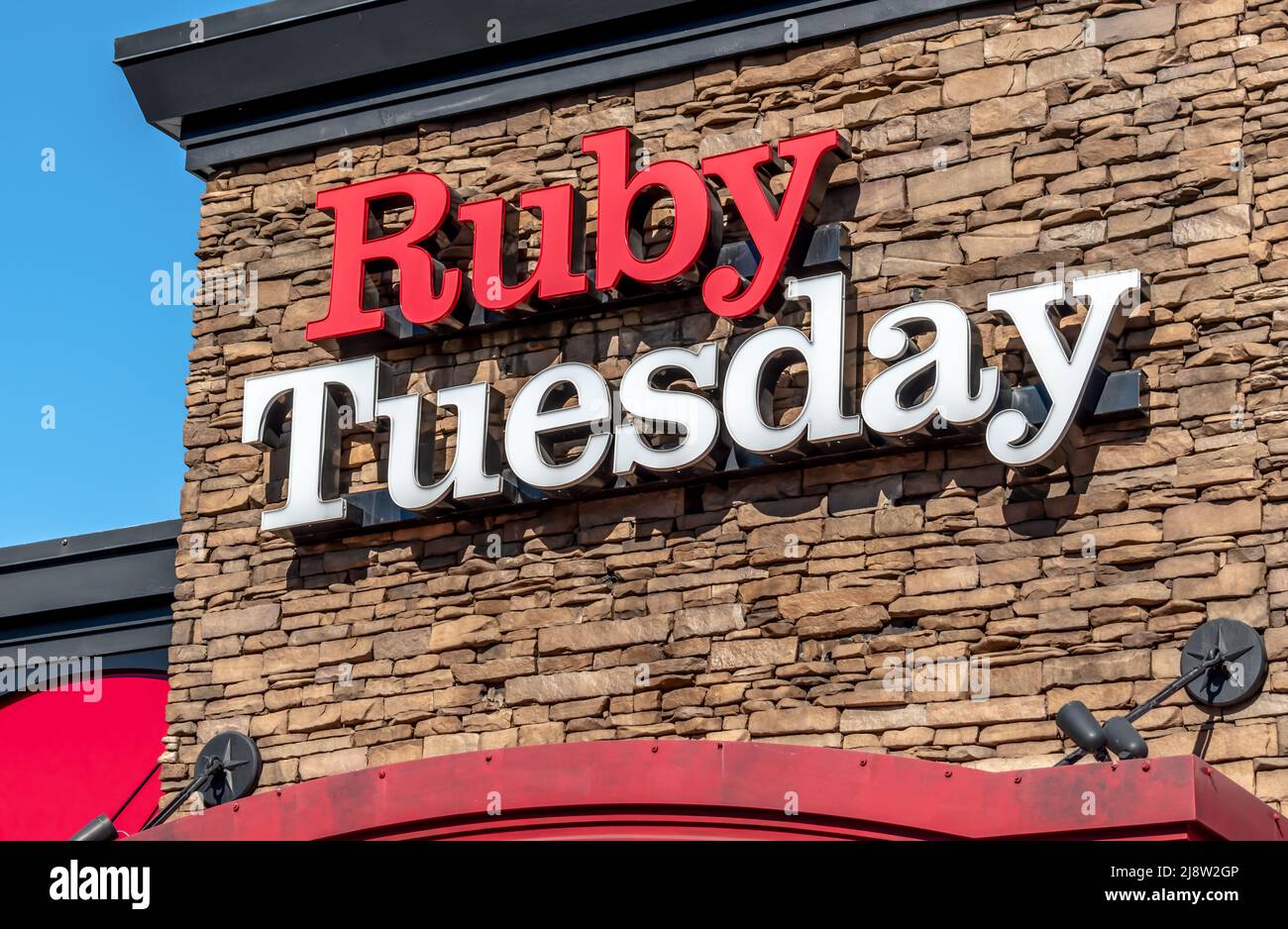 Esterno 'Ruby Tuesday' facciata marchio e logo per esterni in grassetto rosso e bianco lettere su sfondo di pietra in una luminosa giornata di sole. Foto Stock