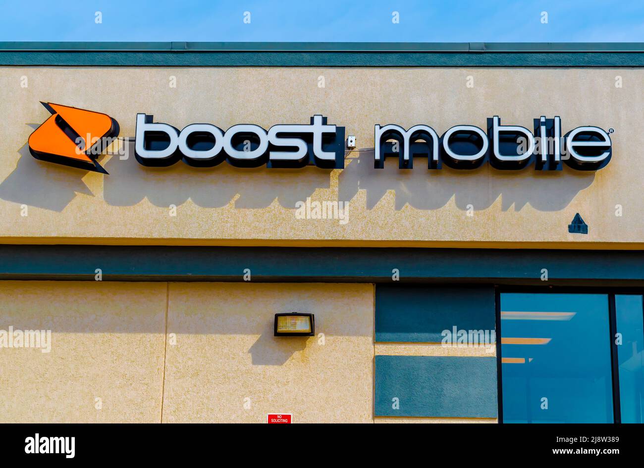 All'esterno, la facciata 'Boost Mobile' e la segnaletica con il logo sopra le finestre di vetro in morbida luce di mattina presto in una giornata di sole con il logo arancione a Charlotte, NC. Foto Stock