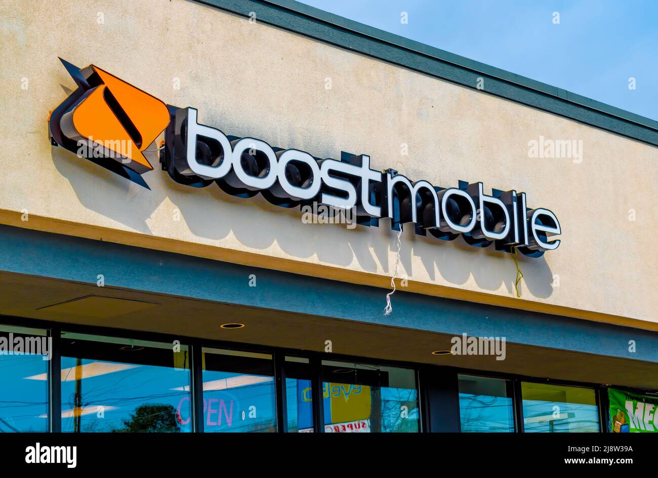 All'esterno, la facciata 'Boost Mobile' e la segnaletica con il logo sopra le finestre di vetro in morbida luce di mattina presto in una giornata di sole con il logo arancione a Charlotte, NC. Foto Stock