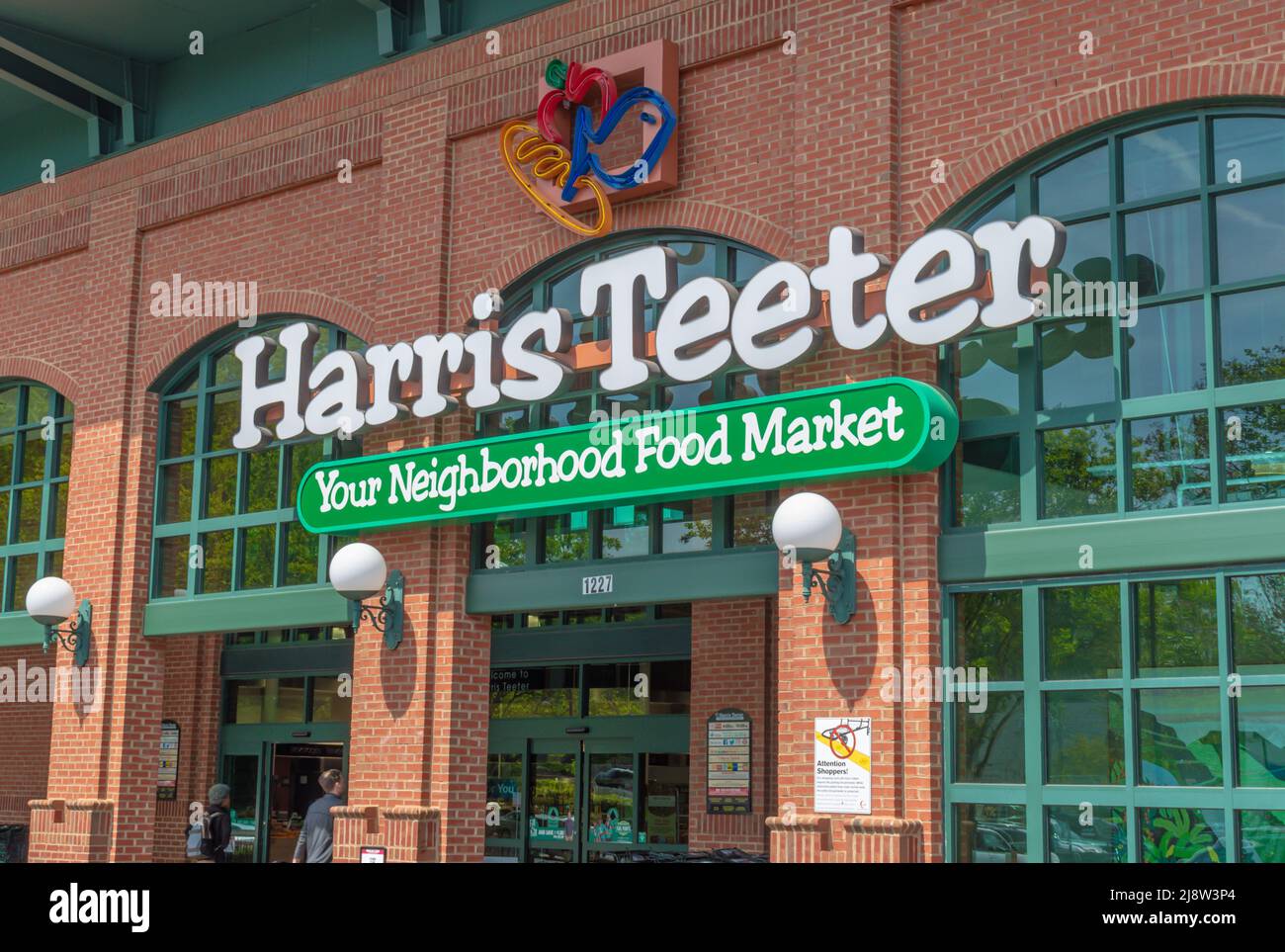 La facciata esterna 'Harris Teeter' presenta un marchio e un logo con colorato logo al neon, finestre in vetro riflettente, globo trasparente accanto all'ingresso alla luce del sole. Foto Stock