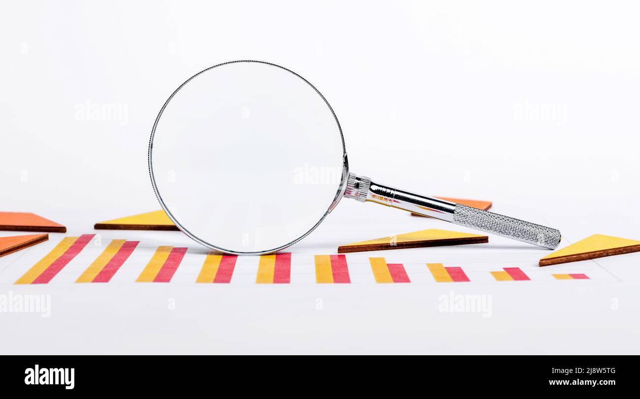 Lente di ingrandimento con grafici che mostrano il rallentamento dello sviluppo aziendale. Crisi economica, analisi del declino del mercato. Concetto di finanza e pianificazione. Foto di alta qualità Foto Stock