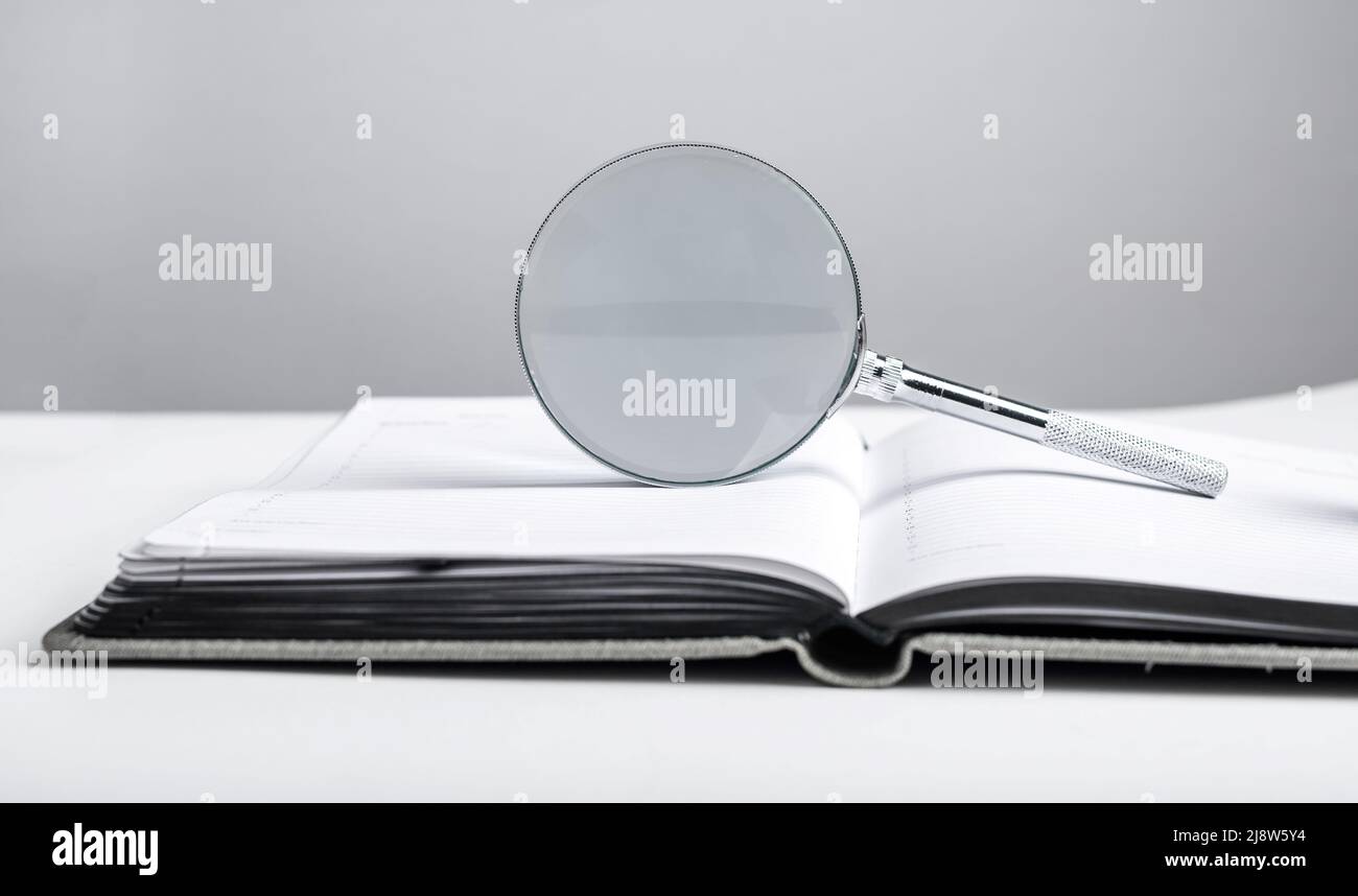 Lente di ingrandimento al pianificatore. Analisi di schedule e note, ricerca di dati importanti in diario. Concetto di gestione del tempo. Foto di alta qualità Foto Stock