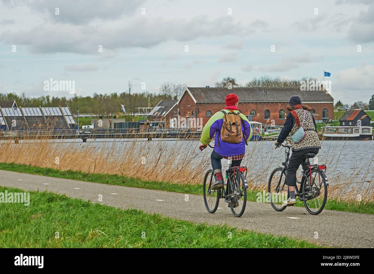 Due persone pedalano lungo un percorso ciclabile a Kinderdijk, Olanda del Sud Paesi Bassi Foto Stock