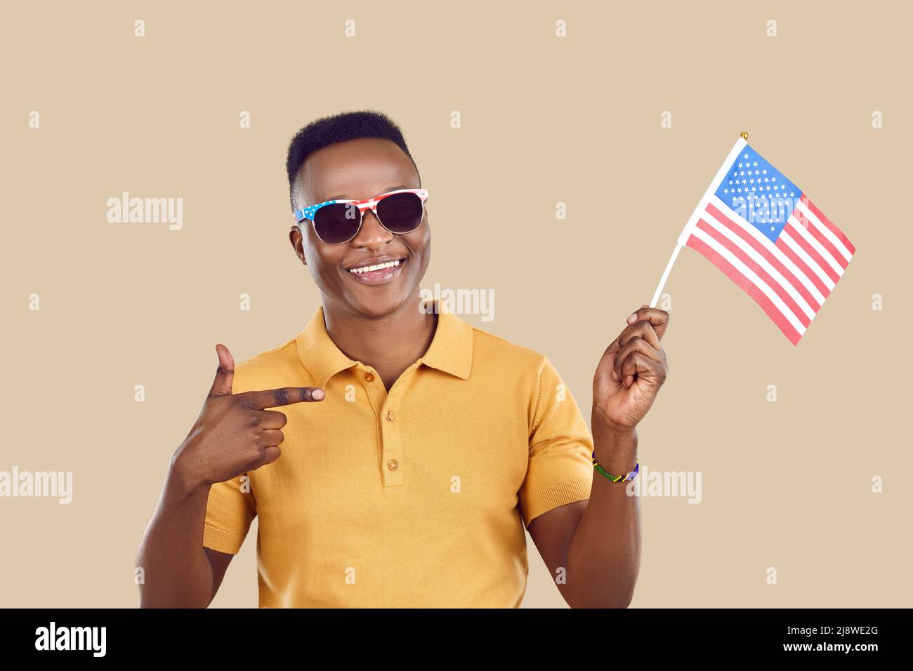 L'uomo felice africano che ha ottenuto la cittadinanza degli Stati Uniti sorride e punta alla bandiera americana nella sua mano Foto Stock