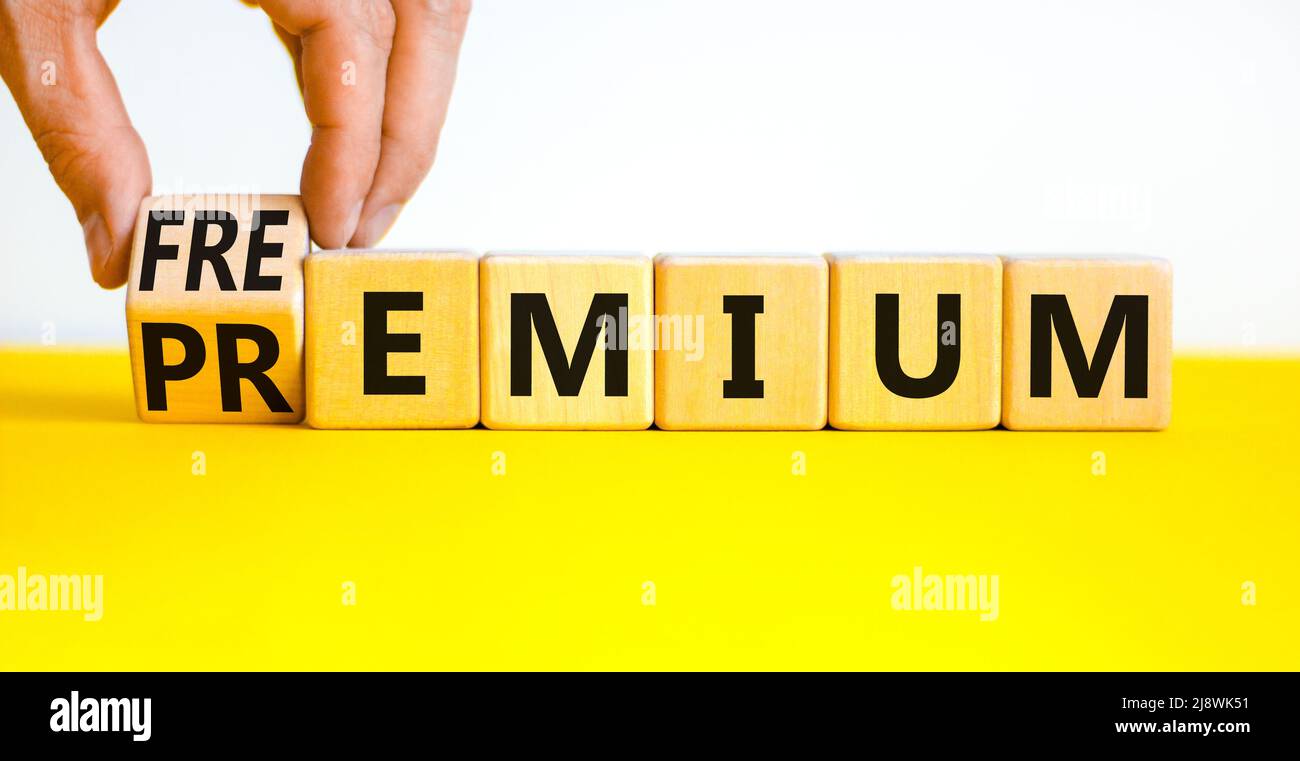 Simbolo Premium o freemium. L'uomo d'affari trasforma i cubi di legno e cambia la parola di concetto Premium in Freemium. Bella tabella gialla sfondo bianco. Foto Stock