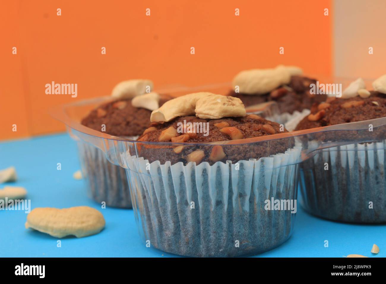 Muffin al cioccolato isolati su sfondo colorato. Delizioso muffin al cioccolato con noci. Foto Stock