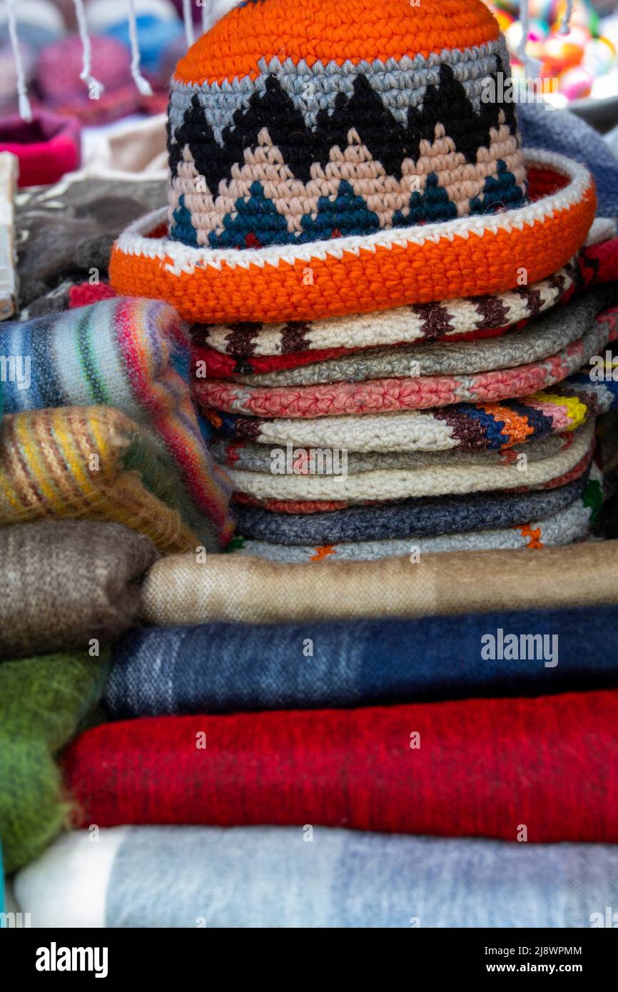 Ecuador, Quito. Mercato Otavalo. Tessuti ecuadoriani tradizionali. Le sciarpe e i cappelli in tessuto tipico di alpaca si mescolano. Foto Stock