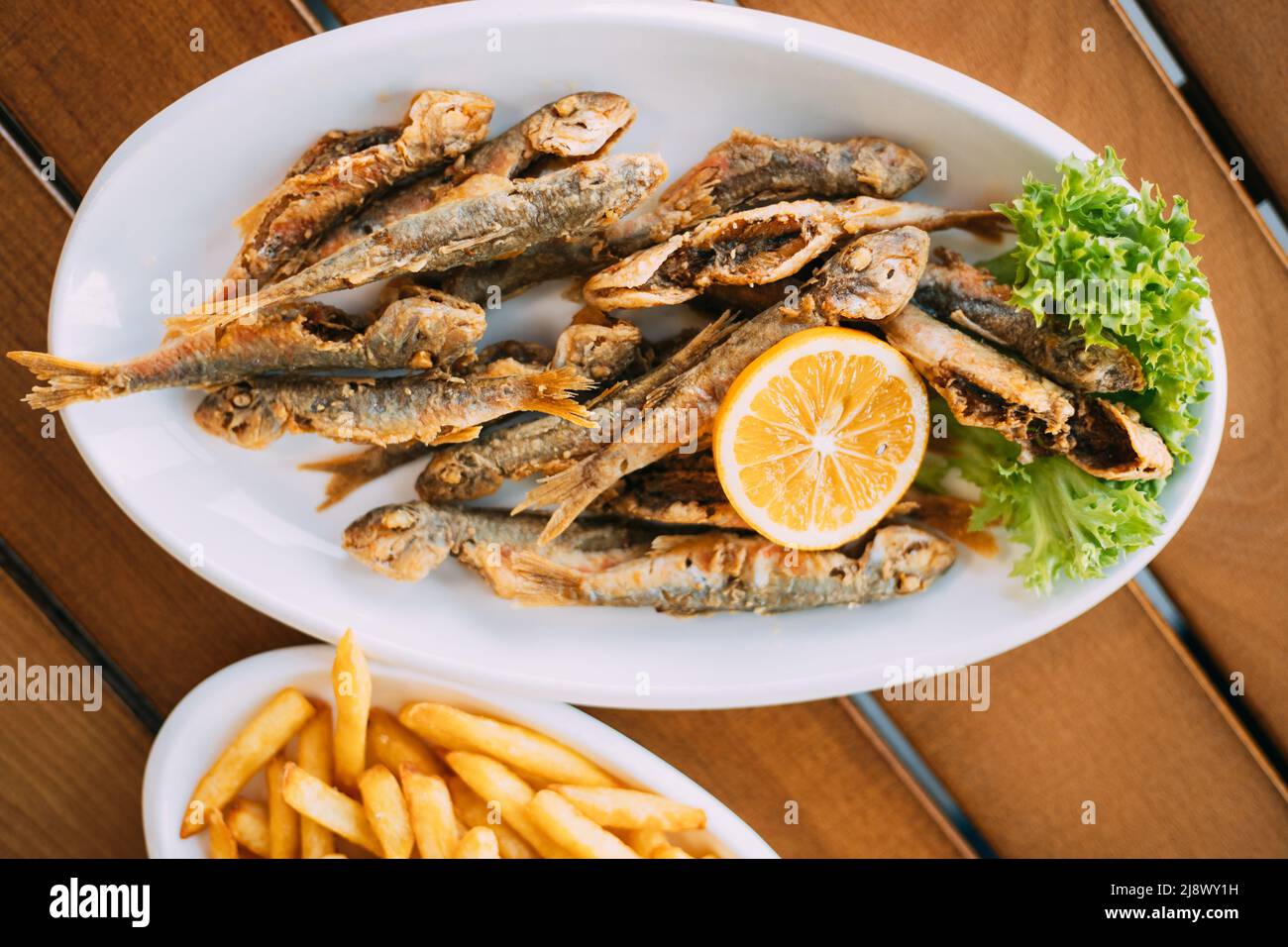 Piatto di cucina nazionale georgiana: Triglie di pesce con patatine fritte e arancioni, pesce e patatine fritte Foto Stock