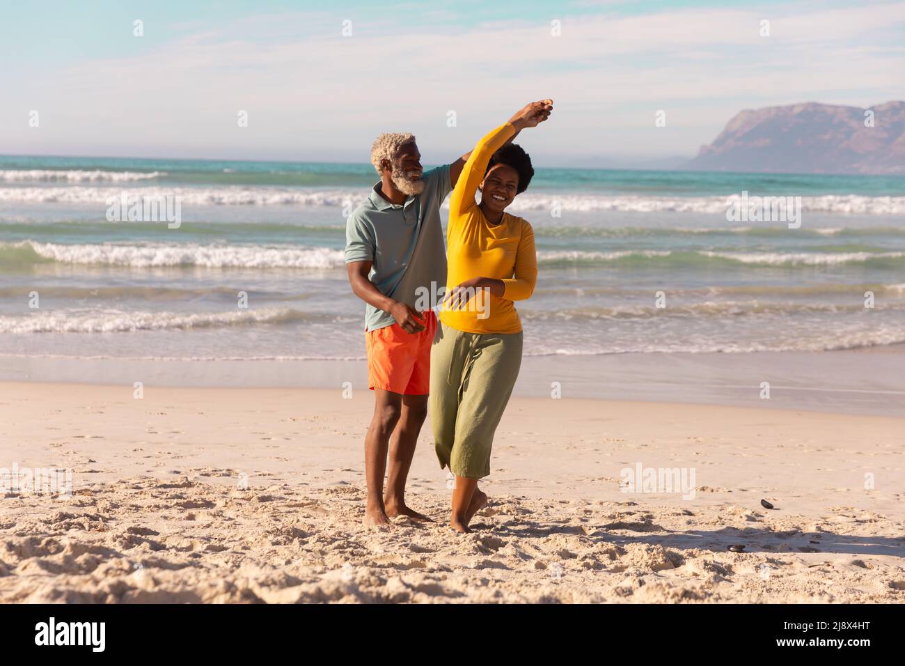 In estate, l'uomo maggiore afro-americano ballava con una donna matura felice contro il mare e il cielo Foto Stock