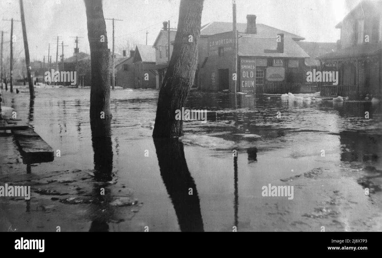 Il lato sud di Bridge Street West a Belleville, Ontario, durante le inondazioni del 1918. E' visibile il negozio di fabbri di George Allen Morton (21 Bridge Street West), con pubblicità per Old Chum Tobacco e Lux e sapone solare Foto Stock
