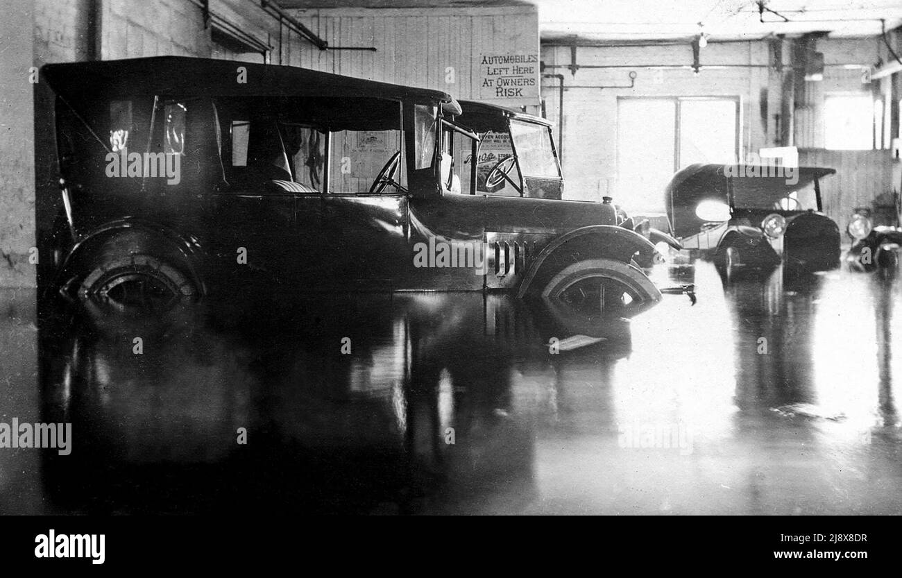 Marzo 1918 alluvione all'interno del McLaughlin's Garage all'angolo nord-est di Bridge Street West e Coleman Street all'estremità ovest del Lower Bridge a Belleville, Ontario. Un cartello sul retro del garage riporta Automobiles lasciato qui a rischio proprietari. 490 Chevrolet in primo piano. CA. 1918 Foto Stock