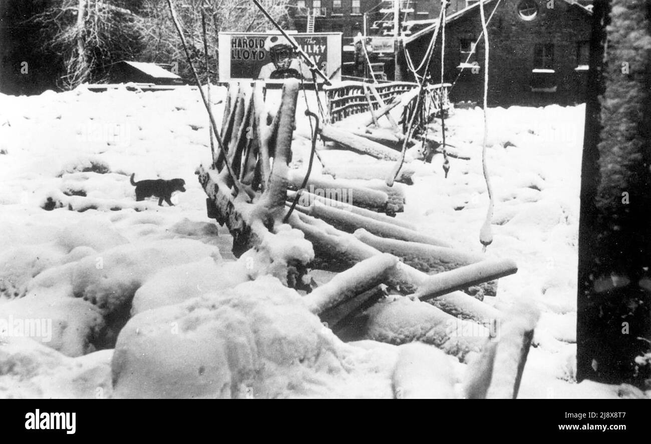 Cartolina del ponte danneggiato a Belleville, Ontario, durante l'alluvione del 1936, che mostra il ghiaccio rompere il ponte. C'è un piccolo cane vicino al ponte e un cartellone pubblicitario Harold Lloyd in 'The Milky Way' sul lato est del fiume Moira ca. 1936 Foto Stock