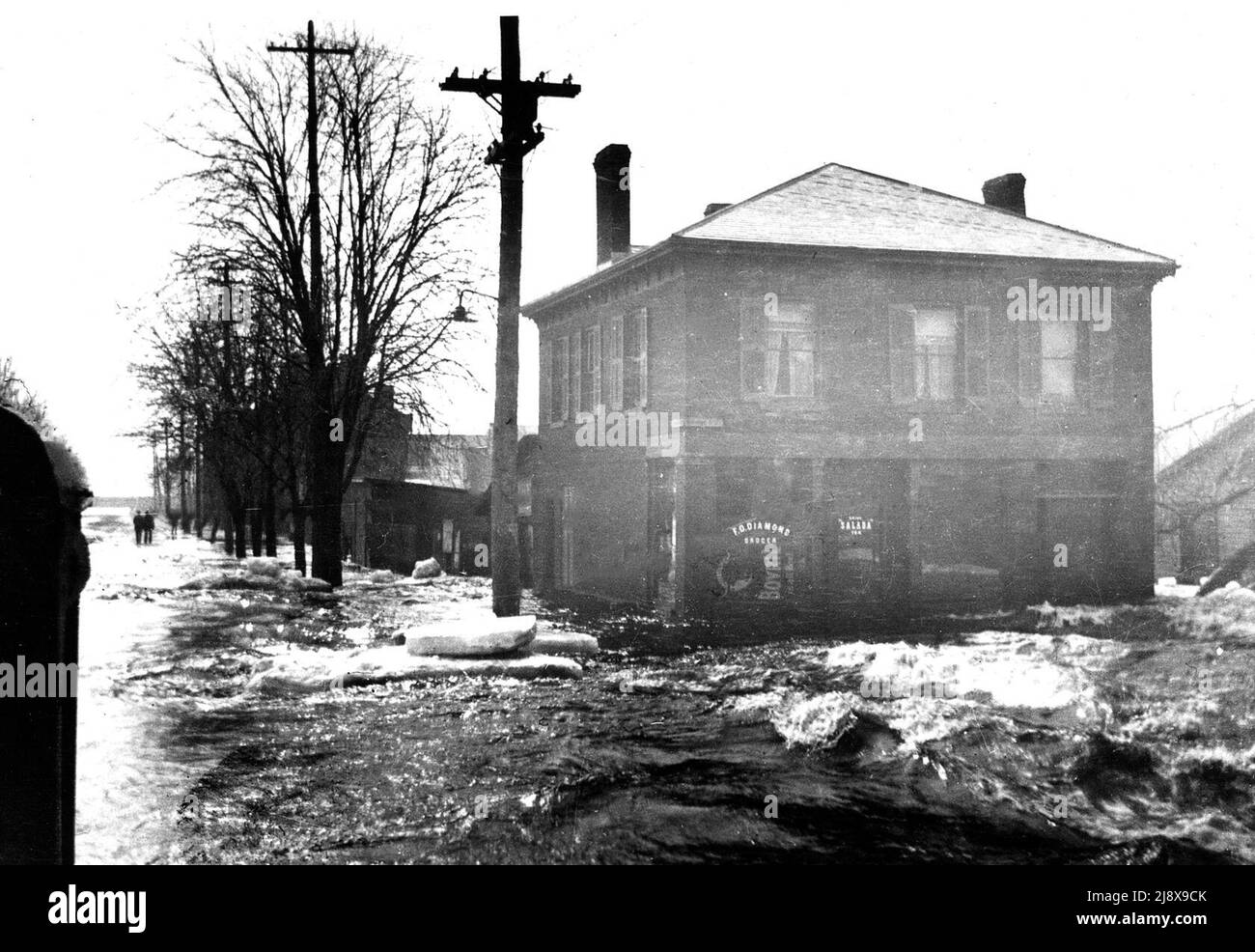 Strada allagata al negozio di alimentari di F.O. Diamond all'angolo sud-ovest di Bridge Street West e Coleman Street nel mese di aprile 1914, Belleville, Ontario, guardando a sud lungo Coleman Street fino alla baia ca. 1914 Foto Stock