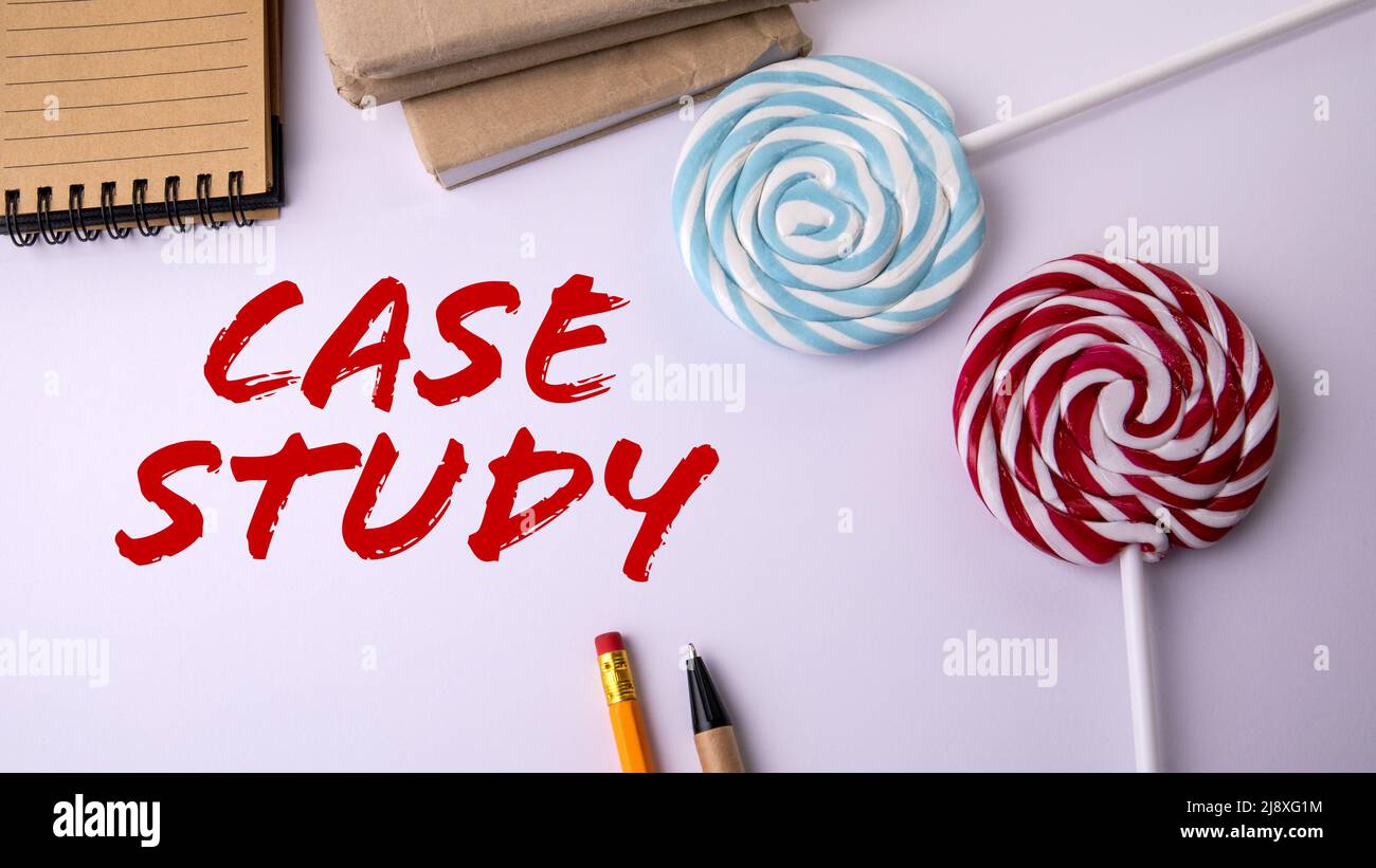 Case study. Forniture per ufficio e caramelle su un bastone su sfondo bianco. Foto Stock