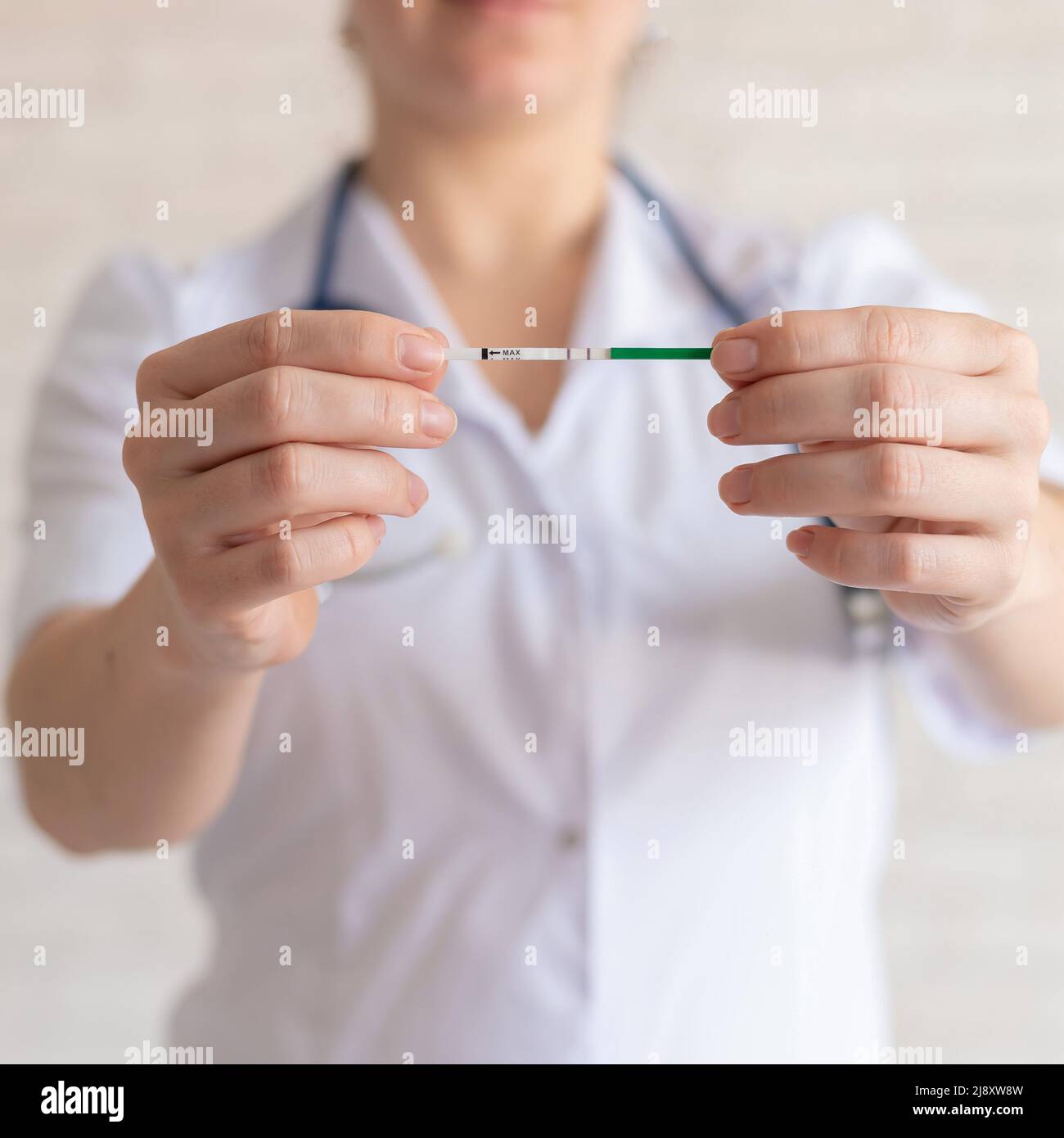 Il medico mantiene un test di gravidanza positivo. Il ginecologo senza volto raccomanda l'uso di test di gravidanza rapida. Foto Stock