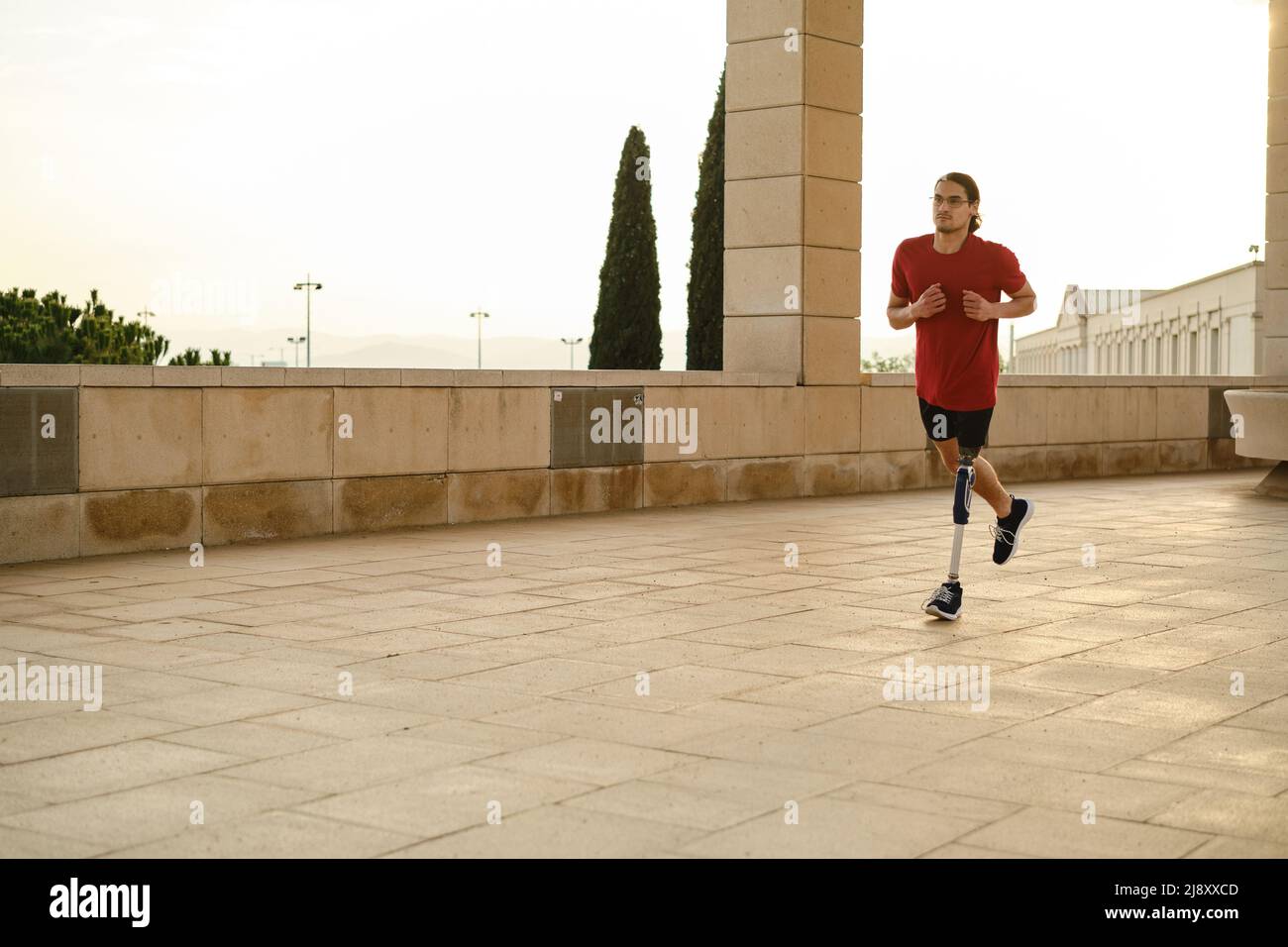 Atleta maschile con disabilità che corre all'aperto. Uomo con gambe protesiche che corrono. Foto Stock