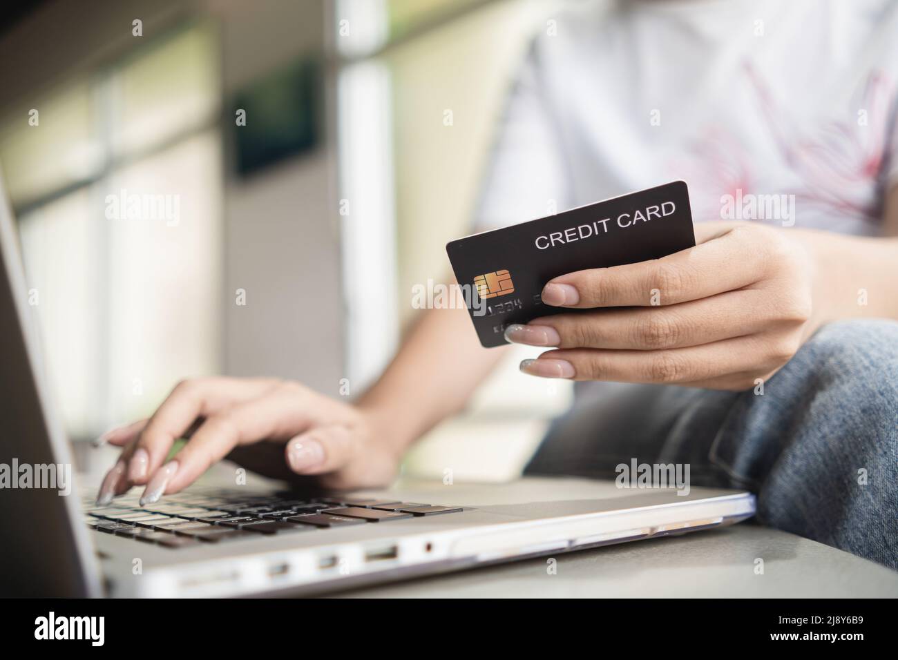 Donna che immette le informazioni della carta di credito per effettuare transazioni sul sito web tramite laptop. Foto Stock
