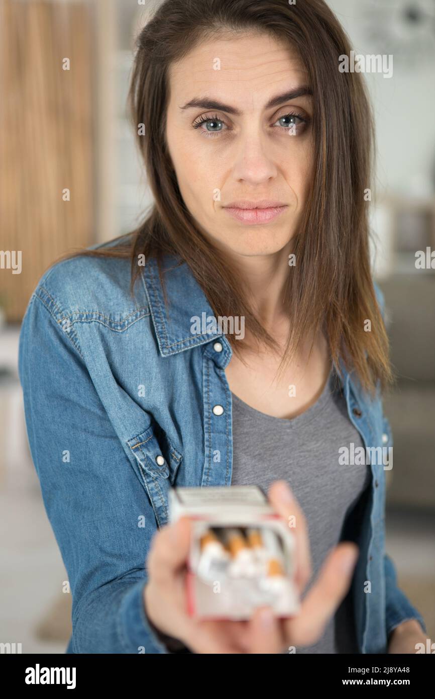 donna con aspetto disordinato che offre una sigaretta Foto Stock