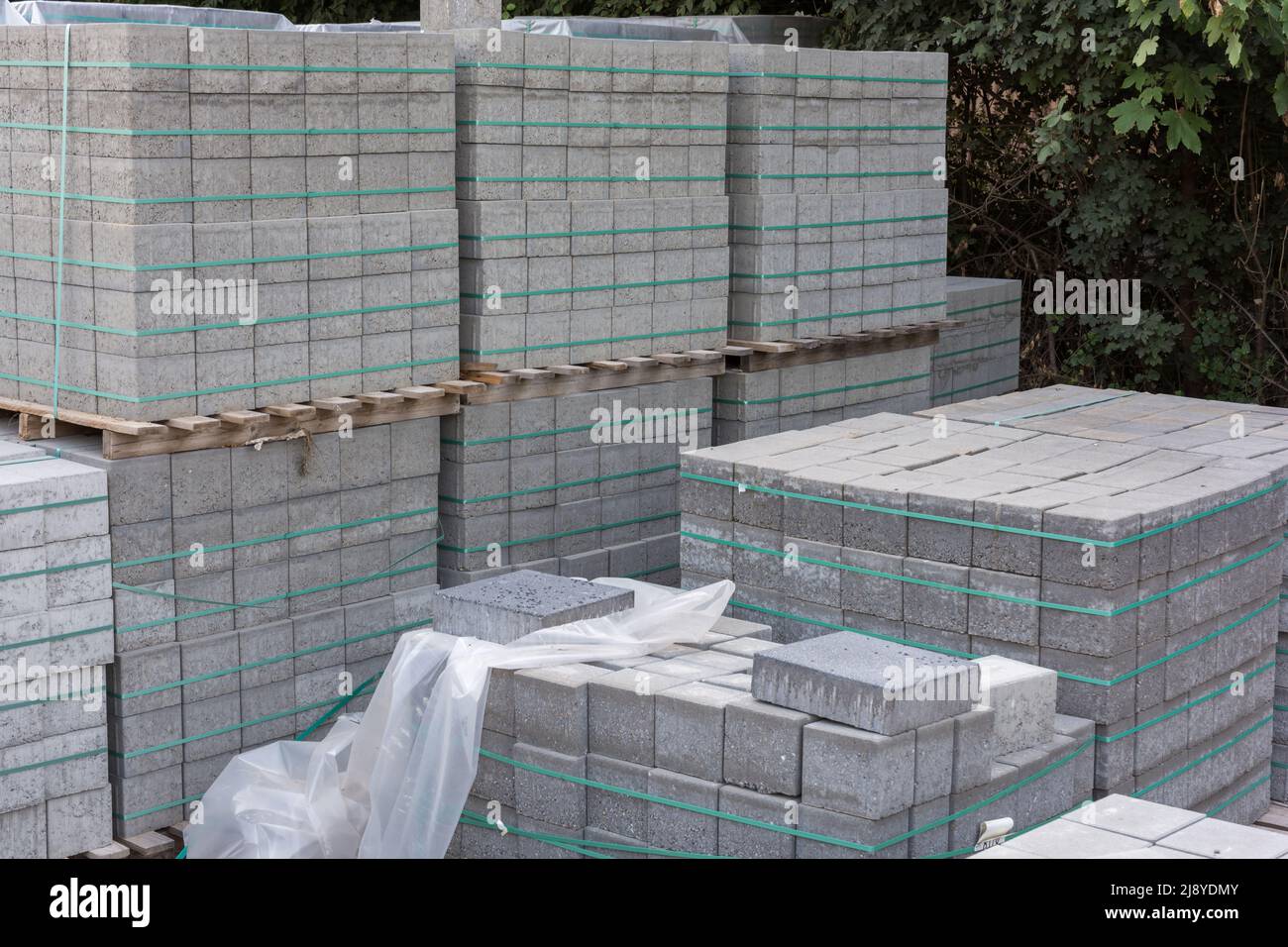 Stoccaggio di diversi pallet pieni di pietre di pavimentazione durante la costruzione di strade Foto Stock