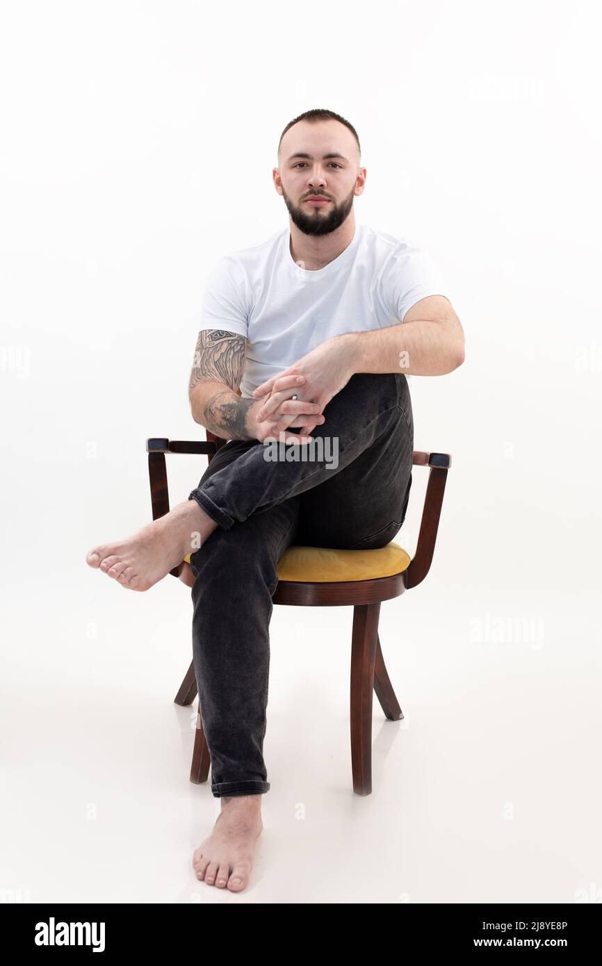 Ritratto verticale tatuato bella bruna, fiducioso, barbearded uomo seduto su sedia. Uomo d'affari di successo Foto Stock