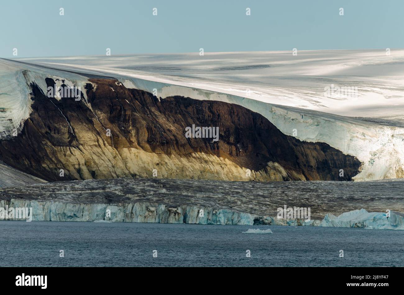 Il ritrattamento del ghiaccio rivela una scogliera di roccia sedimentaria di età giurassica sovrastata dalla lava cretacea nello stretto americano, Franz Josef Land, Russia Foto Stock