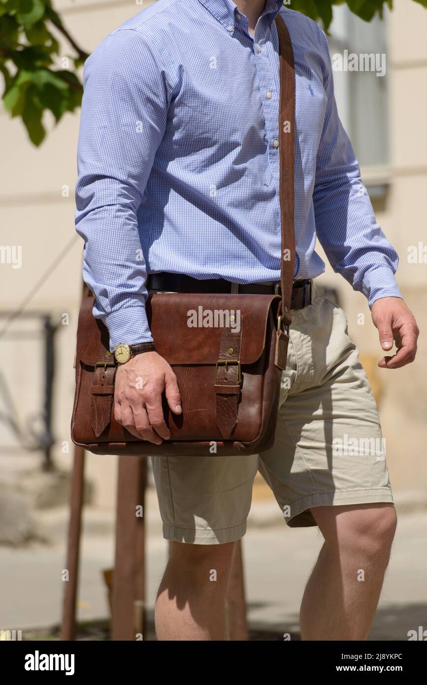 Foto parziale di un uomo con una borsa portadocumenti in pelle marrone dal  look antico e retrò. Foto all'aperto Foto stock - Alamy