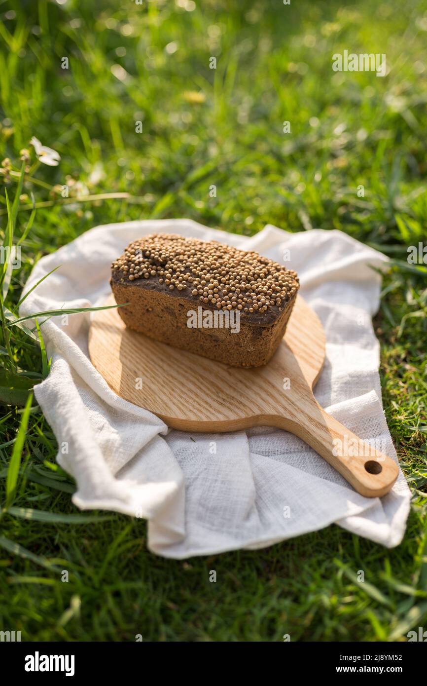 Composizione del pane casereccio su tavola di legno con tovagliolo bianco sull'erba verde. Foto di alta qualità Foto Stock